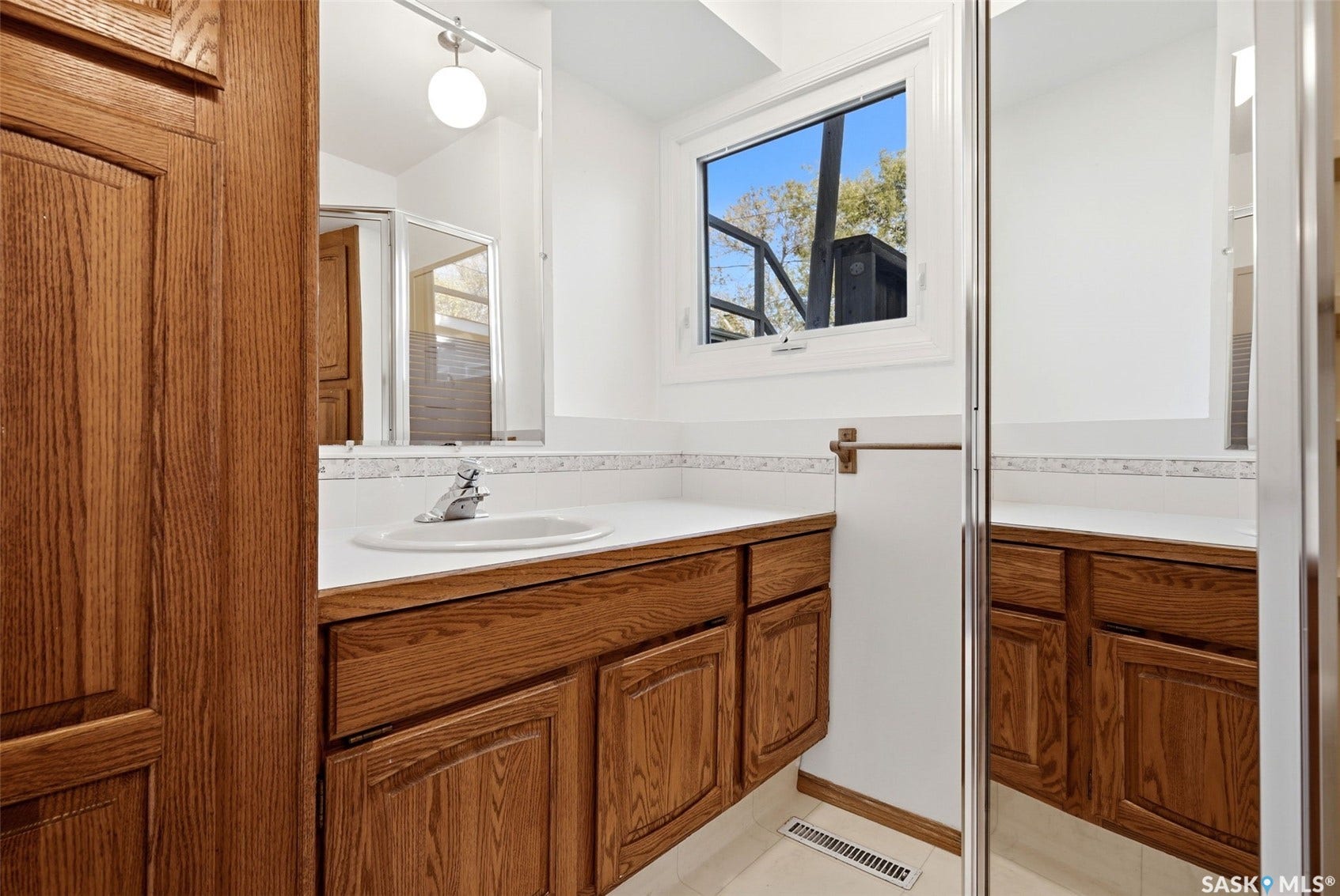 3361 Wascana Street, Regina SK S4S 2H2 Oak wood-finish vanity with an integrated sink, white countertop, and mosaic tile backsplash
