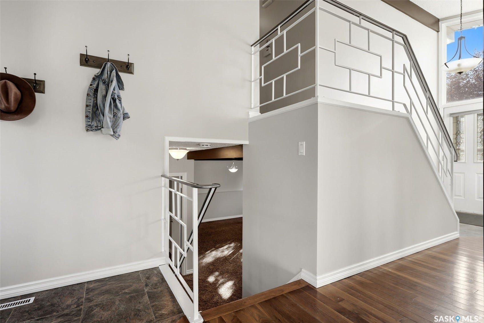 3361 Wascana Street, Regina SK S4S 2H2 Hardwood-finish flooring, staircase with geometric metal railing, tile flooring, white walls, and a front entry door with glass panels