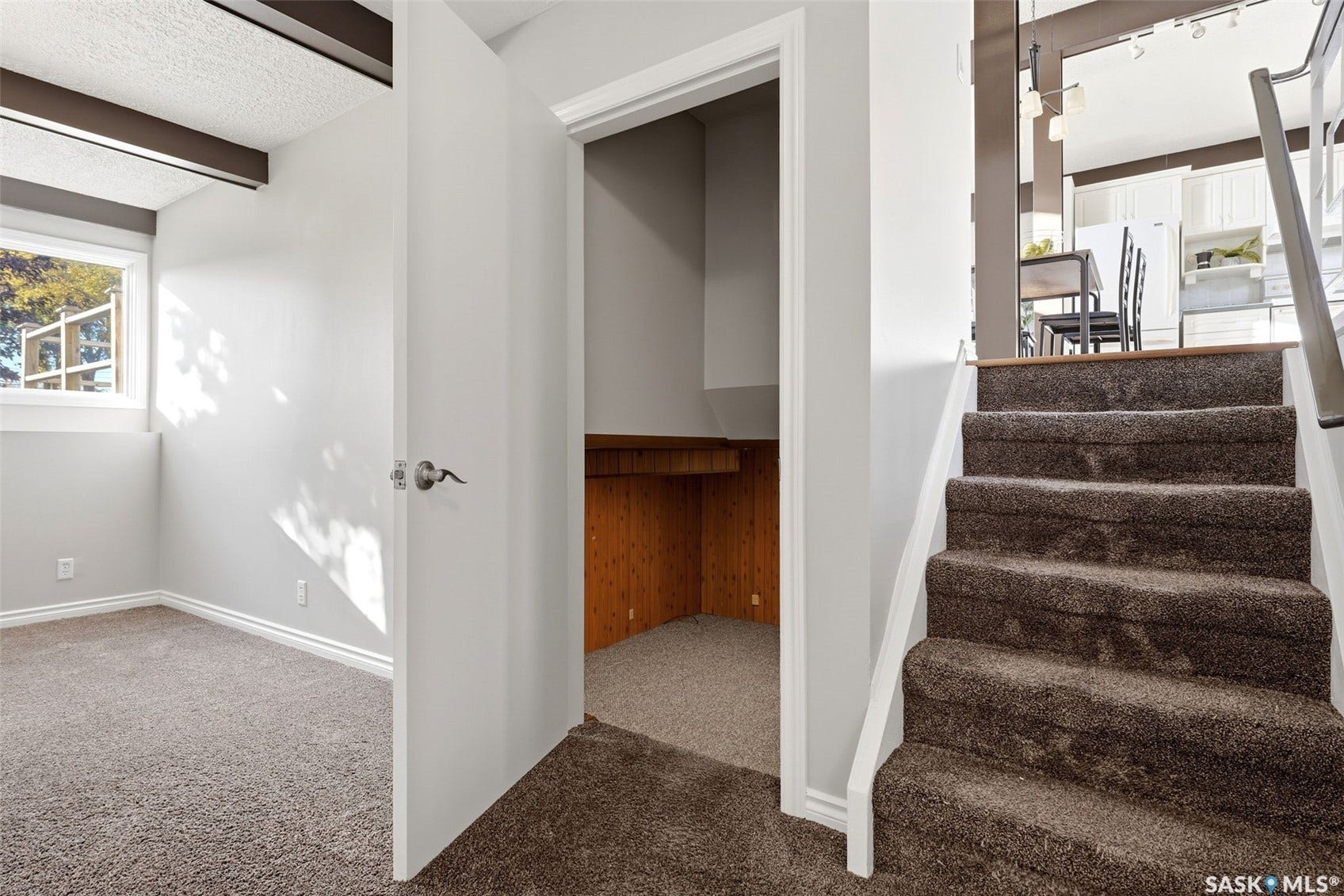 3361 Wascana Street, Regina SK S4S 2H2 Carpeted stairs with white risers, an integrated storage niche with wood-finish paneling, and a separate room featuring a window and carpeted flooring