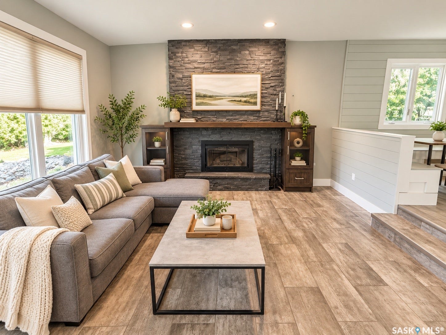 5810 Sherwood Drive, Regina SK S4T 6Y7 Living area featuring a stone-faced fireplace with a wood mantel, built-in cabinetry, wood-finish flooring, and shiplap wall accents