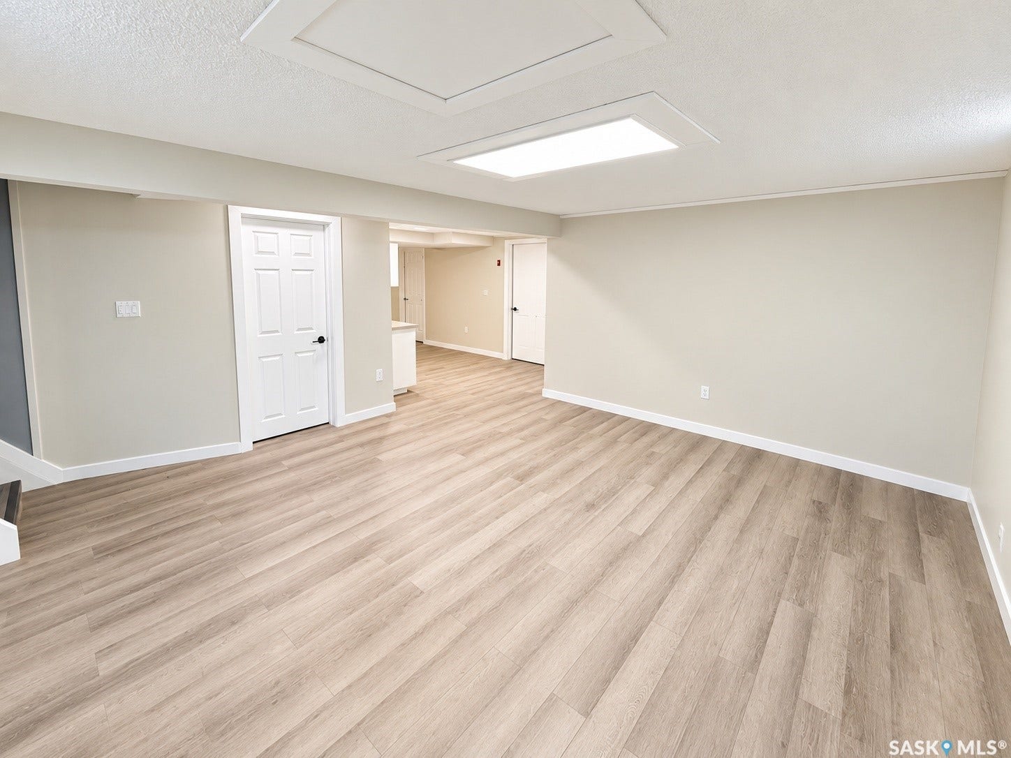 5810 Sherwood Drive, Regina SK S4T 6Y7 Expansive room with neutral wall tones, wood-finish flooring, recessed lighting, and a white paneled door
