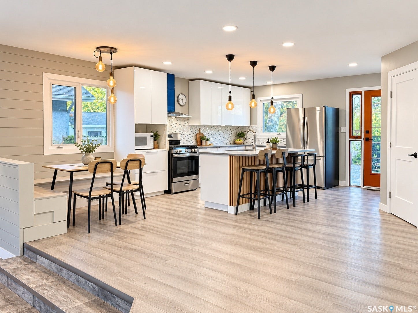 5810 Sherwood Drive, Regina SK S4T 6Y7 Open-concept kitchen with light wood-finish flooring, white cabinetry, a kitchen island with seating, a built-in oven, and a mosaic tile backsplash