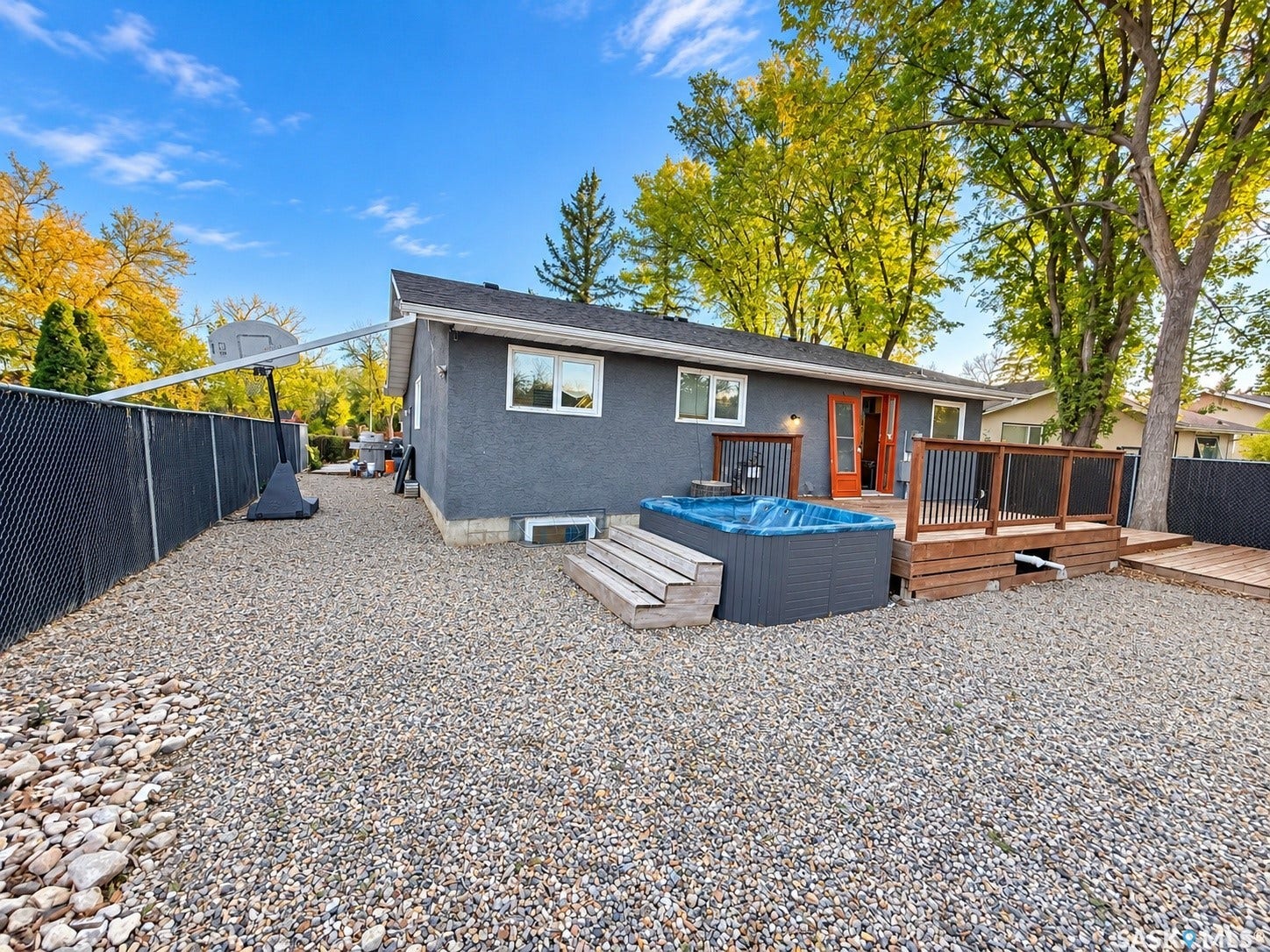 5810 Sherwood Drive, Regina SK S4T 6Y7 Gravel backyard featuring a wooden deck, built-in spa, and privacy fencing