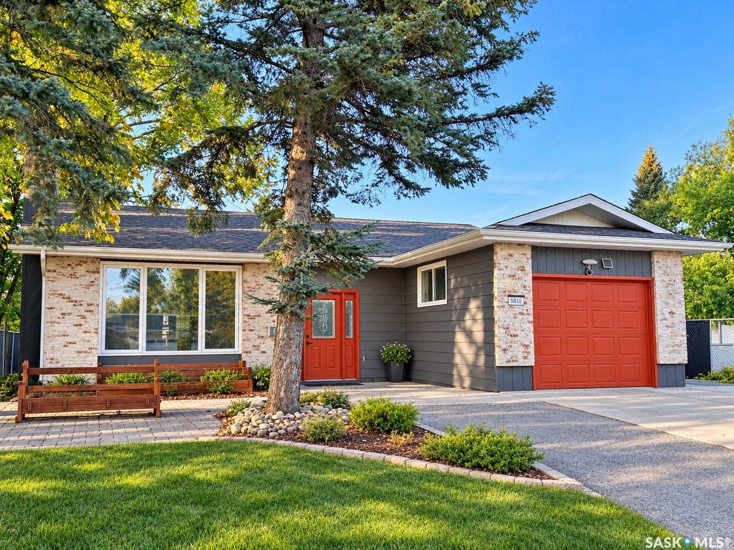 5810 Sherwood Drive, Regina SK S4T 6Y7 Exterior featuring brick and siding facade, large picture windows, a bright red front door, and an attached garage with a matching red door