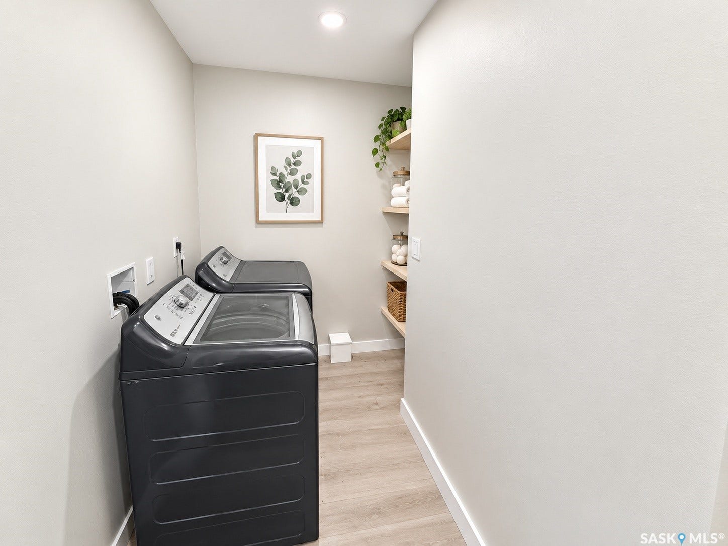 5810 Sherwood Drive, Regina SK S4T 6Y7 Laundry area featuring wood-finish flooring and built-in shelving