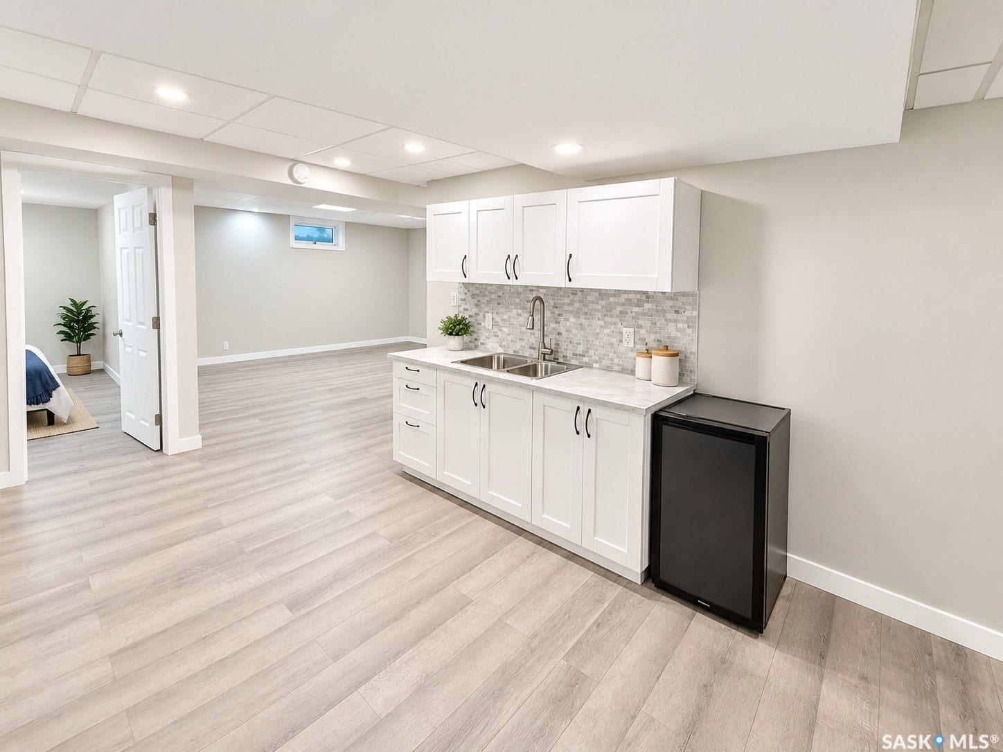 5810 Sherwood Drive, Regina SK S4T 6Y7 Wet bar with white shaker cabinets, dual basin sink, and mosaic tile backsplash