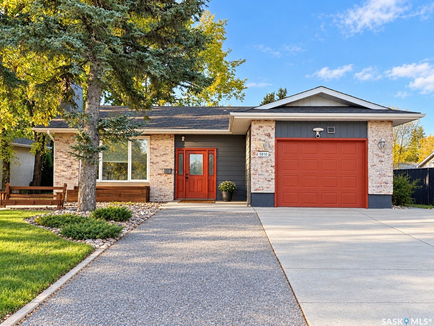 5810 Sherwood Drive, Regina SK S4T 6Y7 Exterior featuring brick and horizontal siding, a vibrant orange entry door, and a matching orange garage door