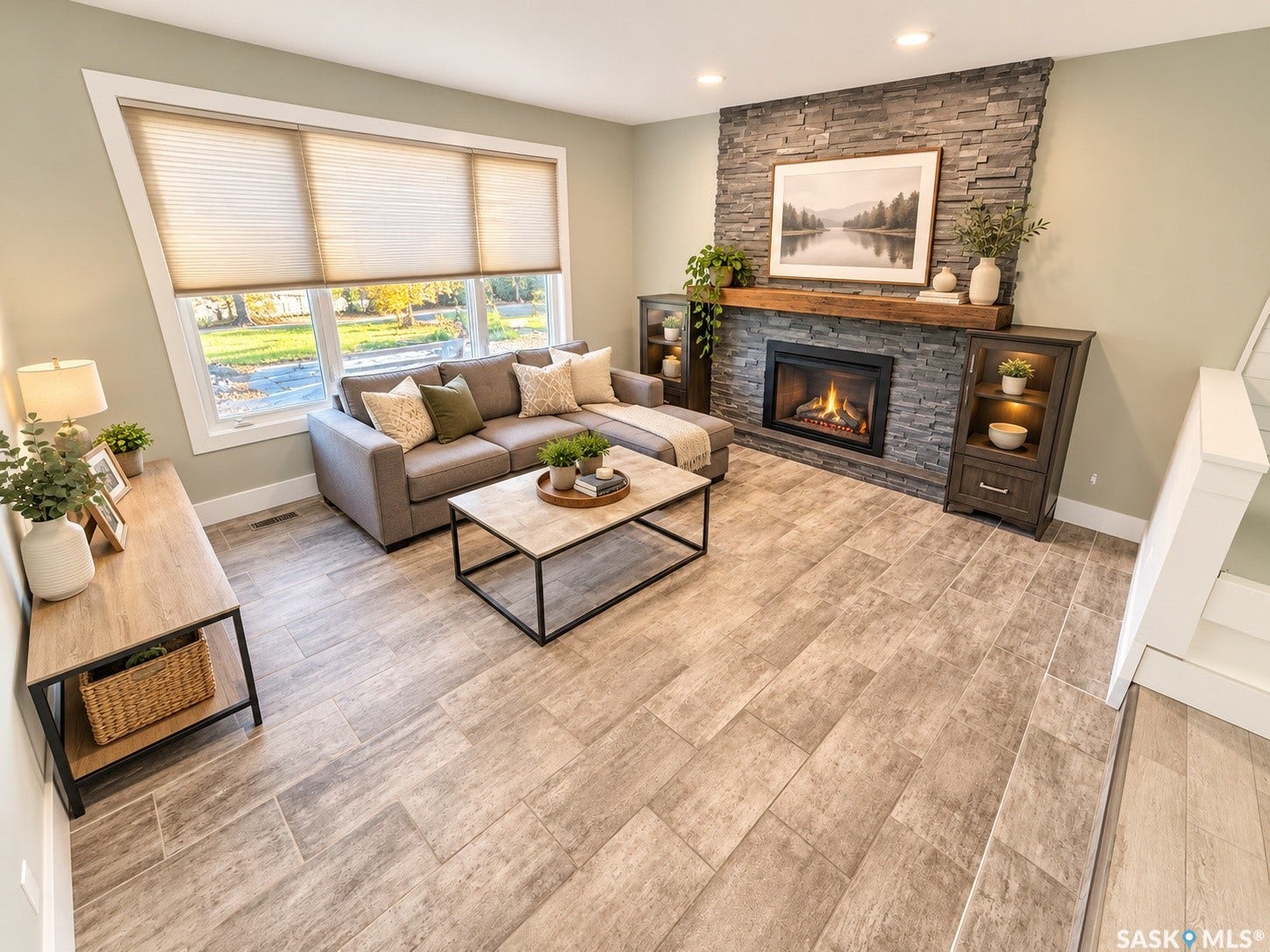 5810 Sherwood Drive, Regina SK S4T 6Y7 Spacious living area featuring large windows, a stone-clad fireplace with a wood mantel, built-in display cabinetry, and wood-finish flooring