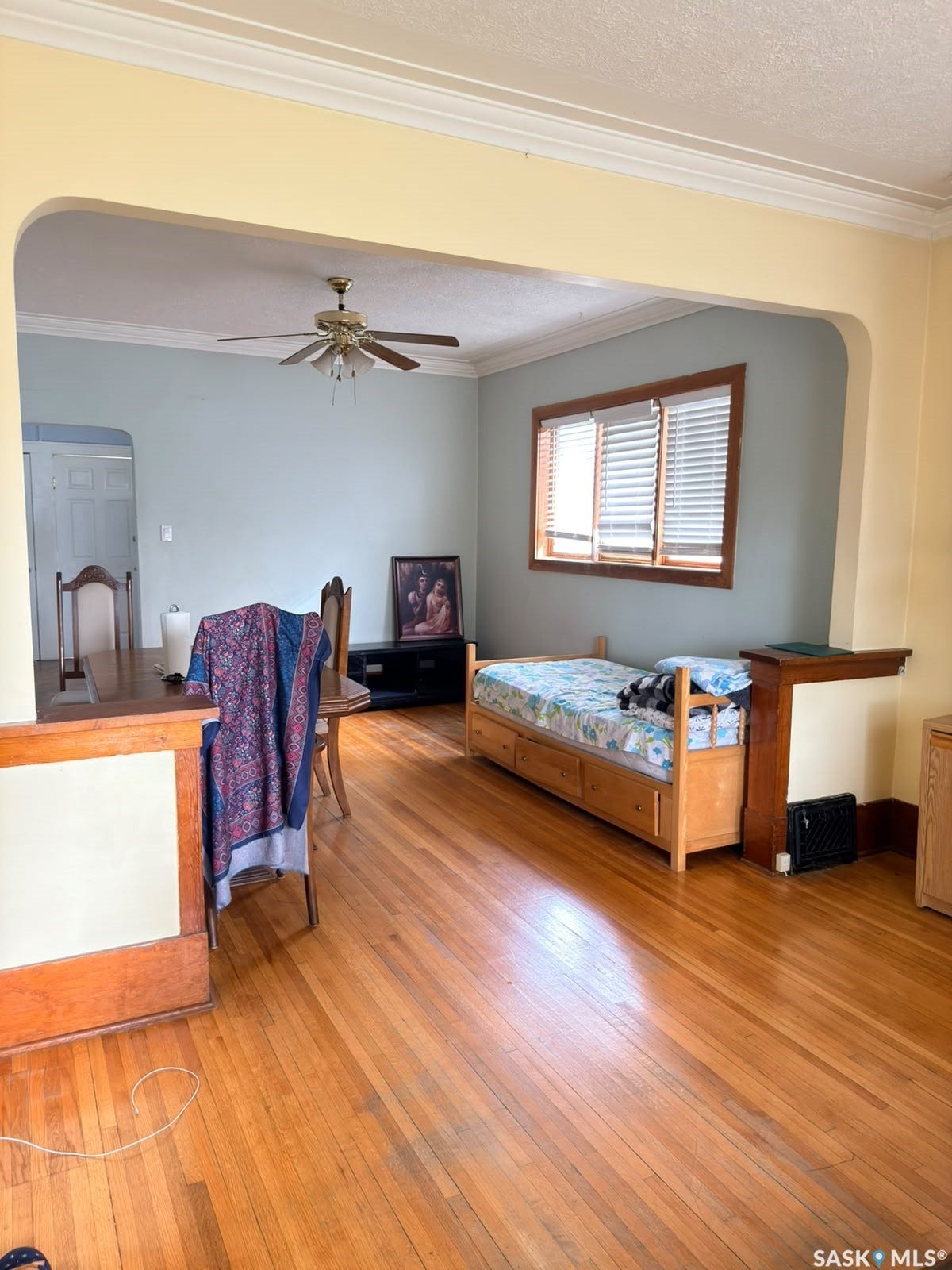 Hardwood flooring throughout, crown molding, arched entryways, and a ceiling fan with integrated lighting