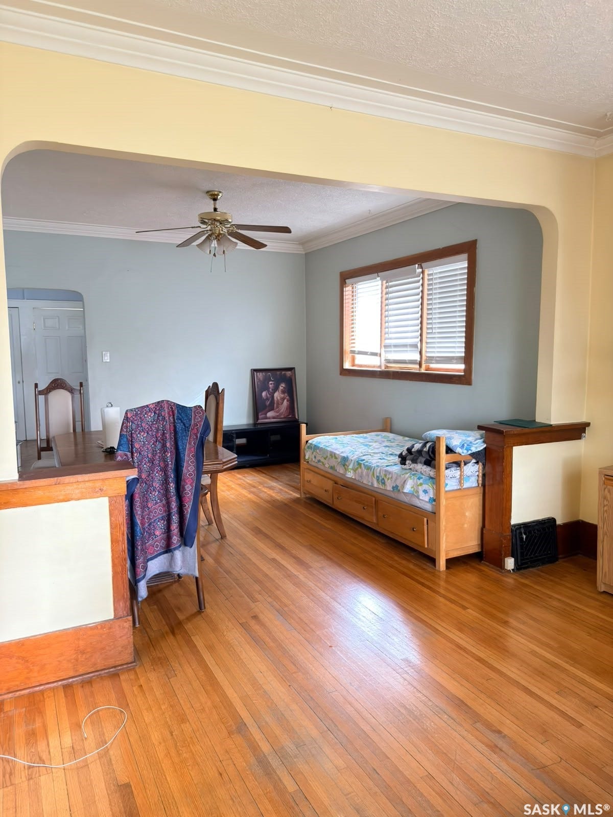 Hardwood flooring, arched doorway, crown molding, ceiling fan, wooden window trim