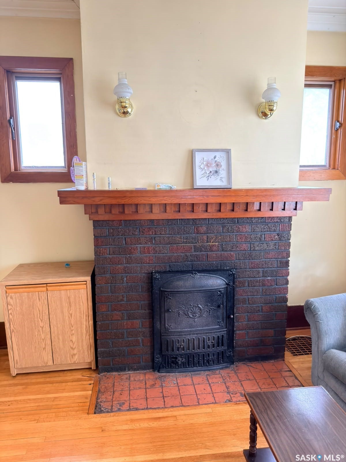 Brick fireplace with a dark metal firebox, wood mantel, and tile hearth