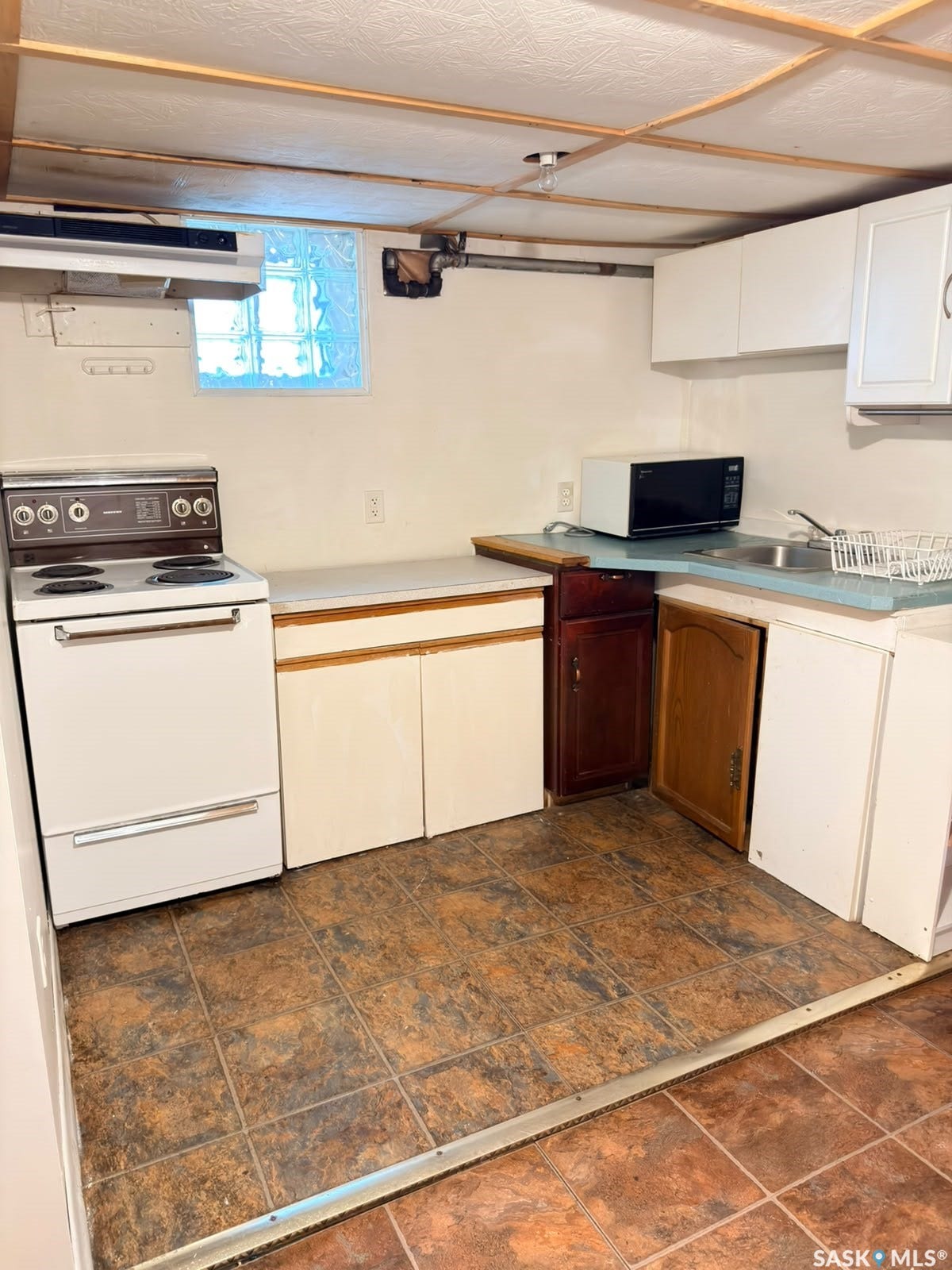Kitchenette featuring an electric range, base cabinetry, upper cabinetry, a sink, and tile flooring