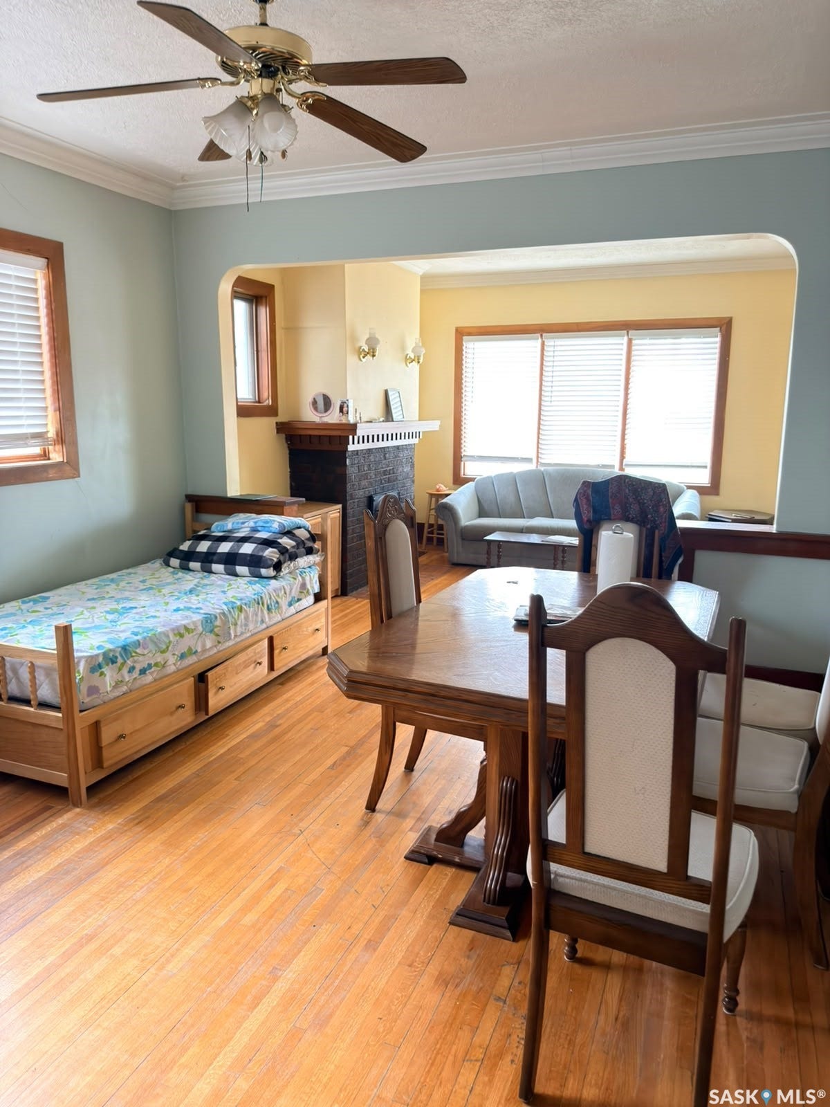 Hardwood flooring throughout, archway entry between rooms, decorative crown molding, ceiling fan with integrated lighting
