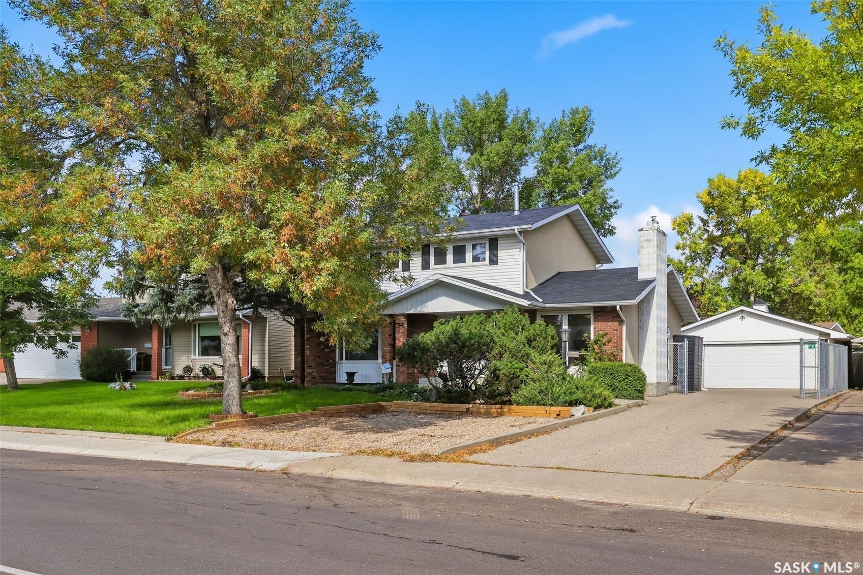 Two-story residence with a multi-level roofline, a prominent brick chimney, and an attached garage with a white door