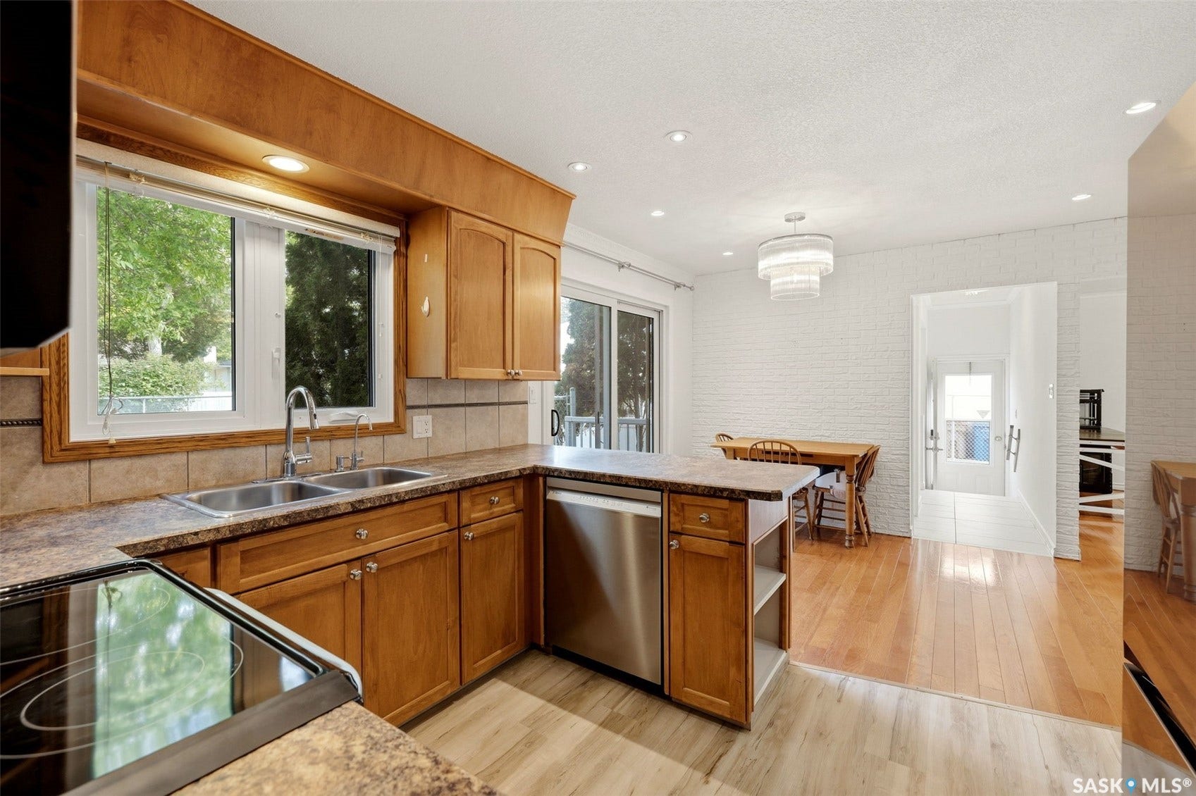 Kitchen featuring wood cabinetry, stainless steel dishwasher, dual basin sink, and recessed lighting