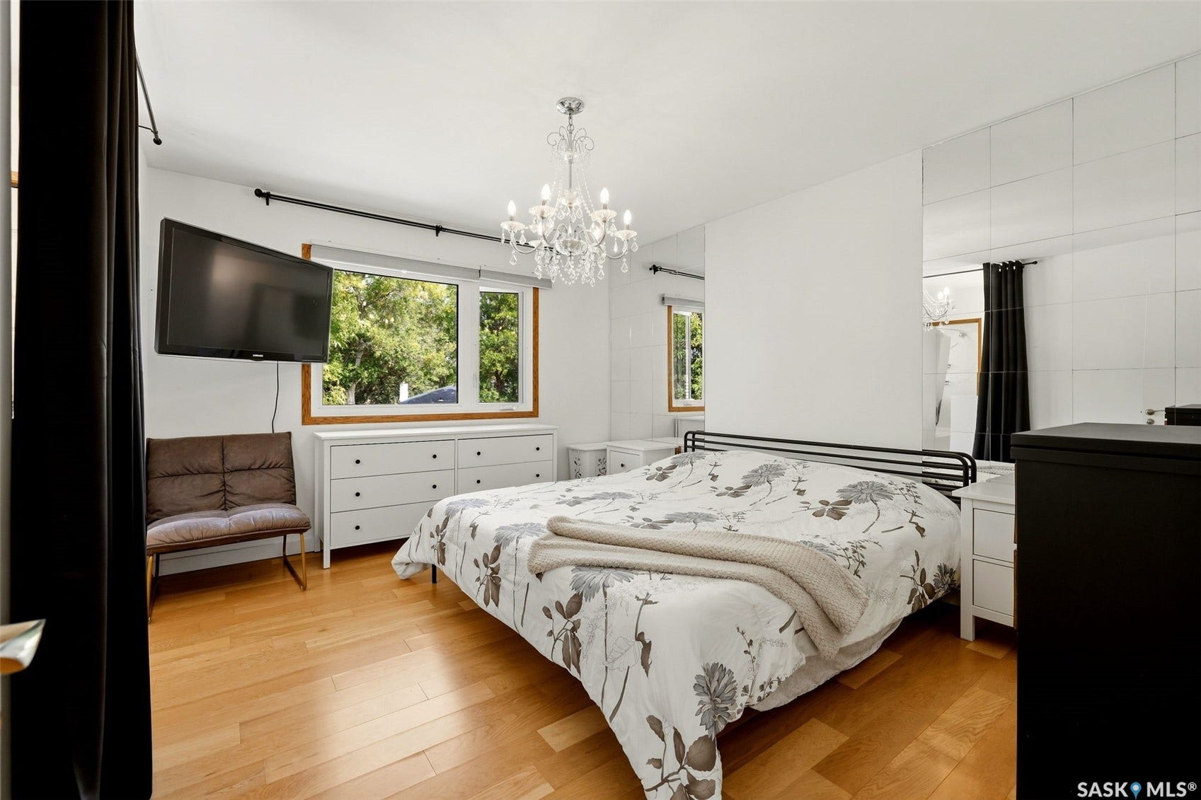 Hardwood flooring, wall-mounted television, multi-pane window, crystal chandelier, mirrored wall panels