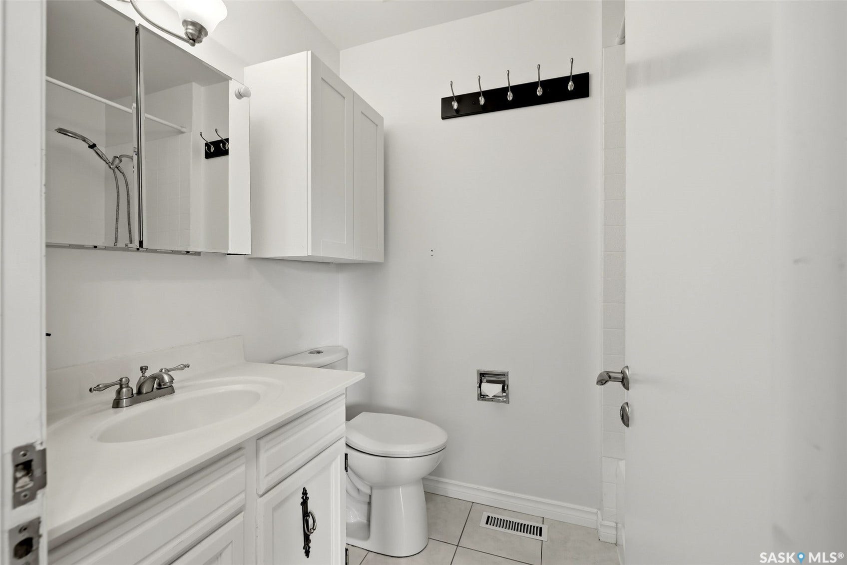 Vanity with integrated sink, wall-mounted mirror cabinet, white wall cabinetry, and flush-mount lighting
