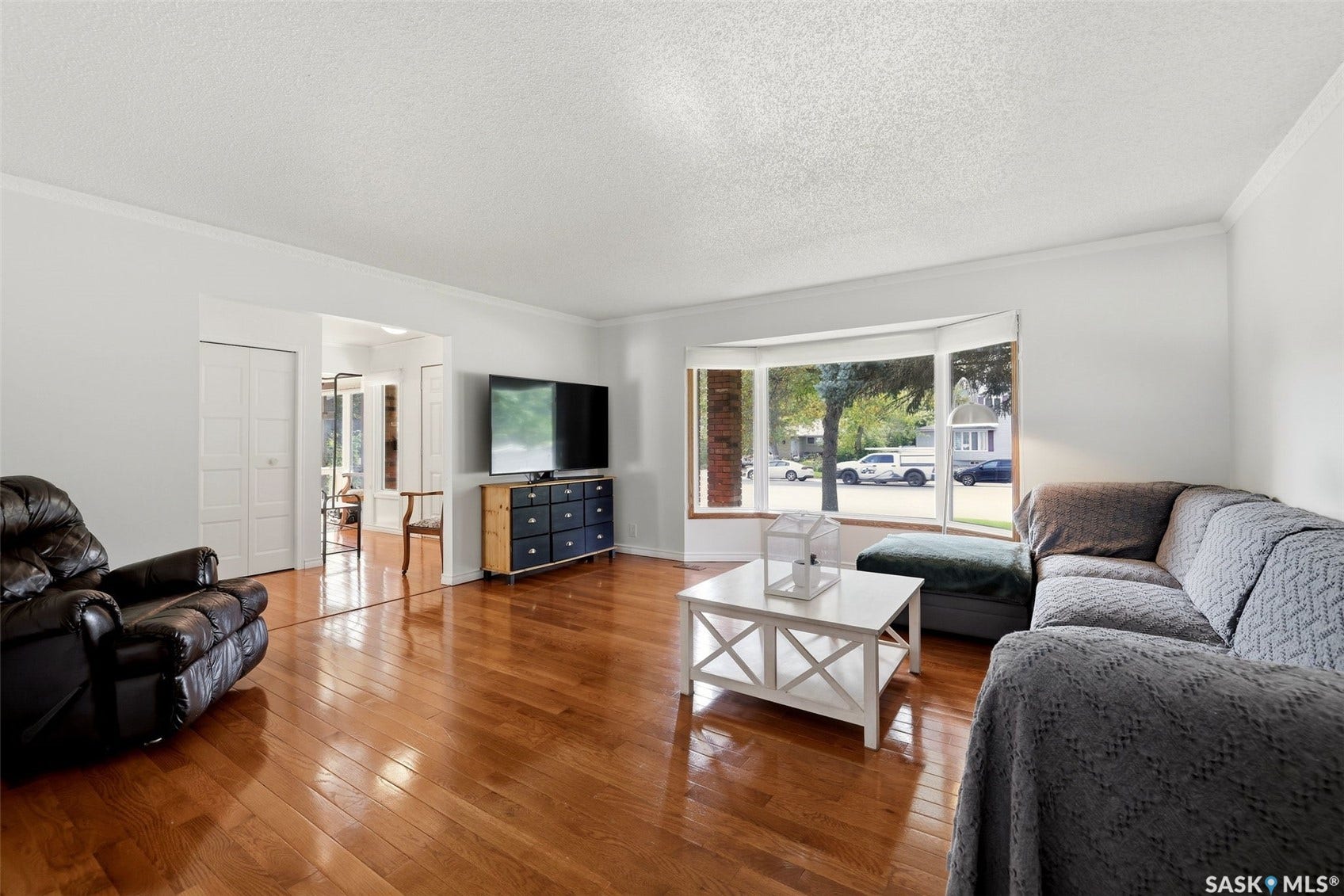 Hardwood flooring, bay window, white trim, crown molding, and a wide entryway