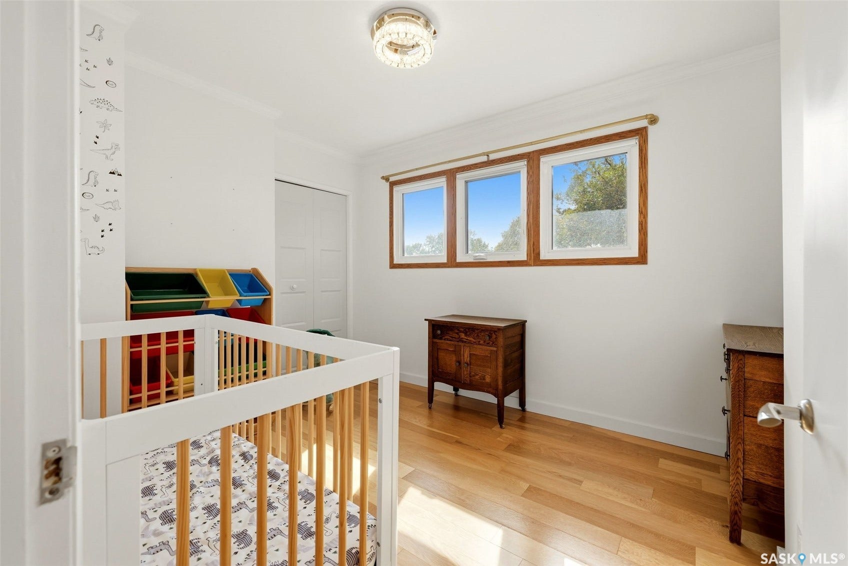 Hardwood-style flooring, three pane windows with wood frames, white walls, and a bi-fold closet door