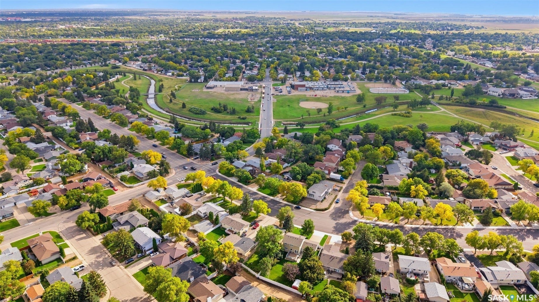 Mature residential neighborhood with tree-lined streets, extensive green spaces, and a winding creek