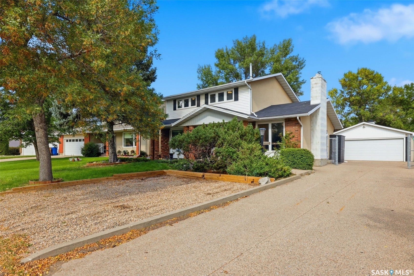 Two-story residence featuring brick and stucco siding, a prominent exterior chimney, and a detached garage with a white overhead door