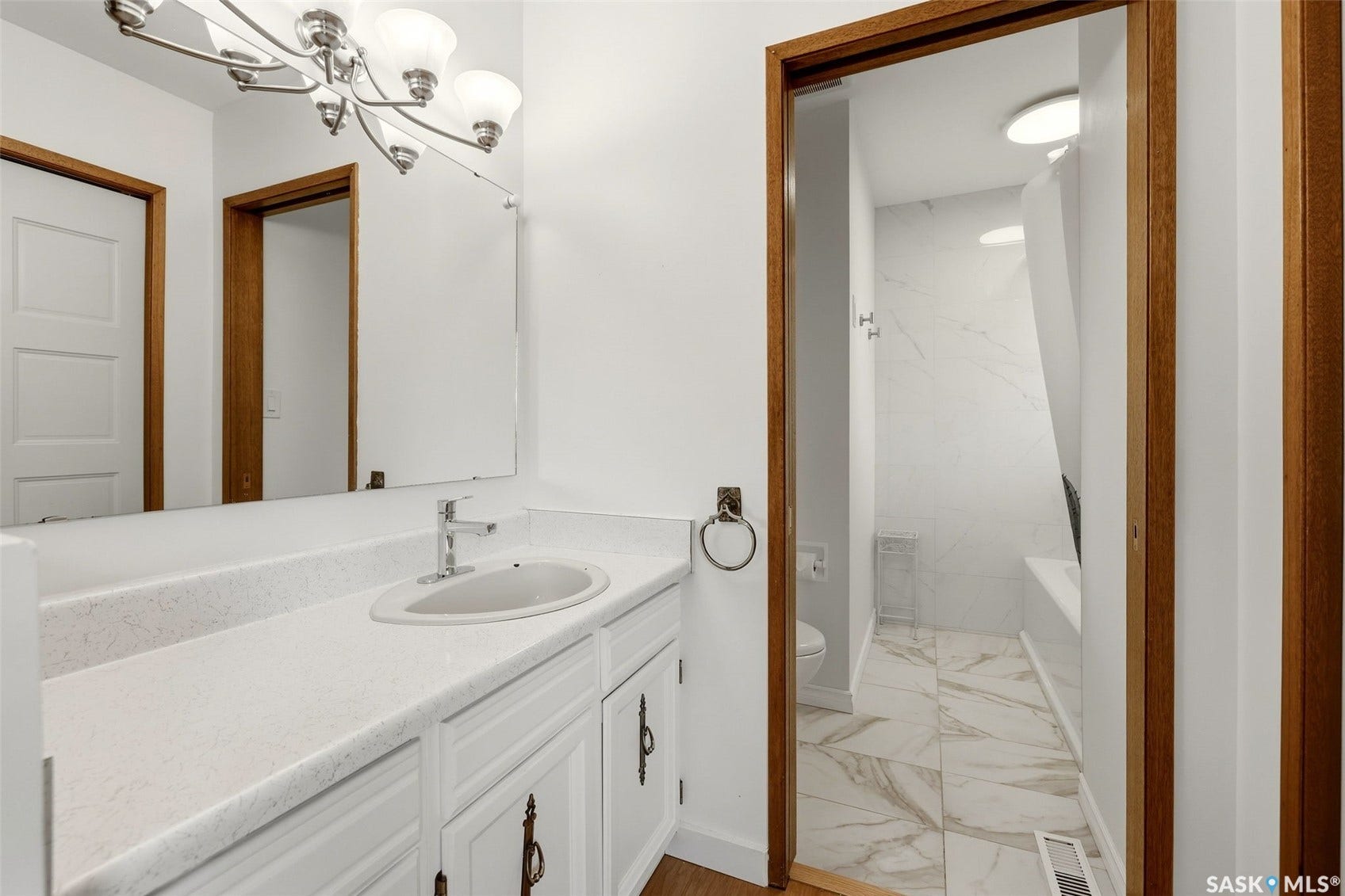 Bathroom vanity with a white countertop and integrated sink, brushed nickel faucet, and a large wall-mounted mirror