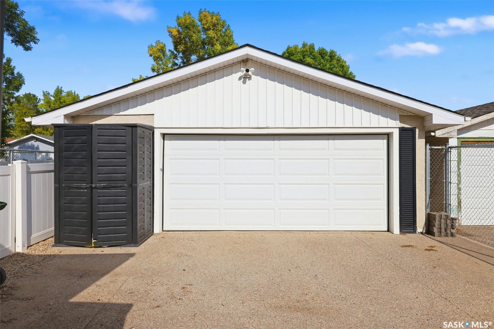 Attached garage with a white panel door, white vertical siding, and an asphalt shingle roof