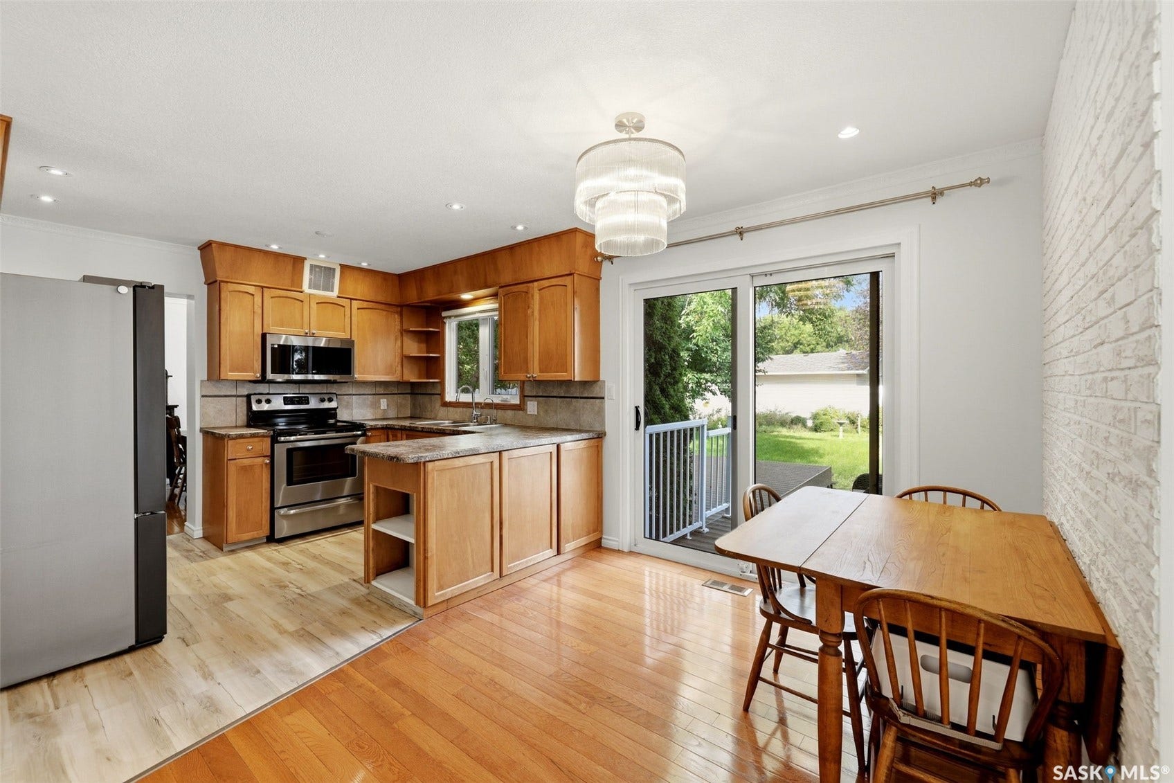 Kitchen featuring wood cabinetry, stainless steel appliances, a center island with countertop, and wood-finish flooring