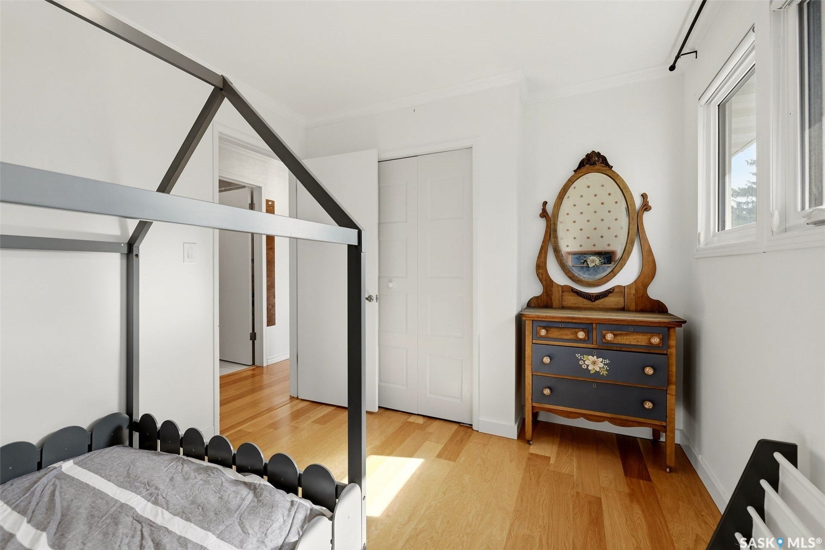 Hardwood flooring, painted walls, white trim, and a window with natural light