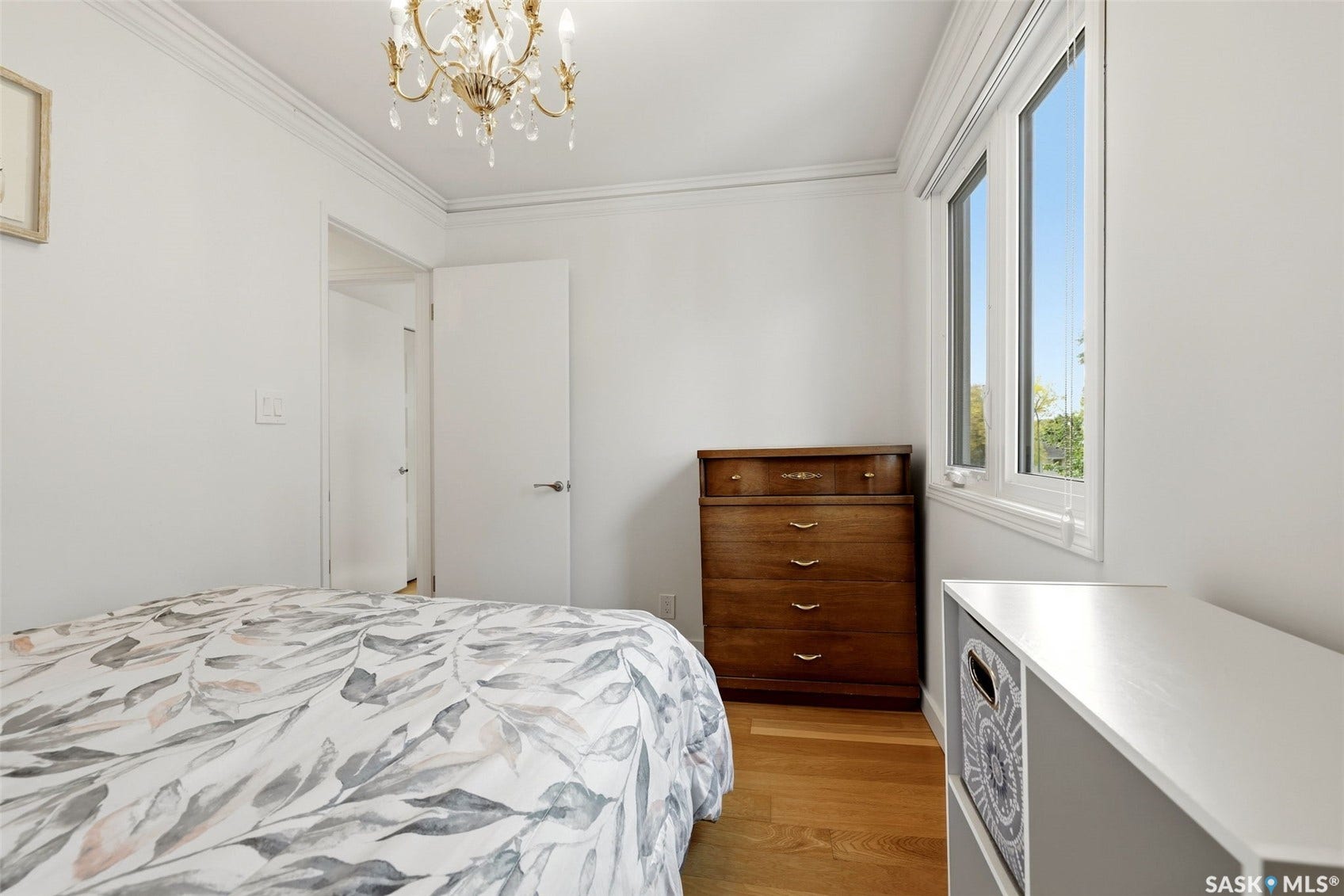 Hardwood-style flooring, crown molding, and a chandelier with crystal accents