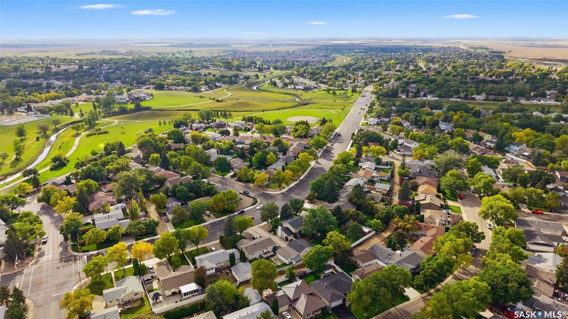 Expansive residential area with mature trees, green spaces, and a winding road network