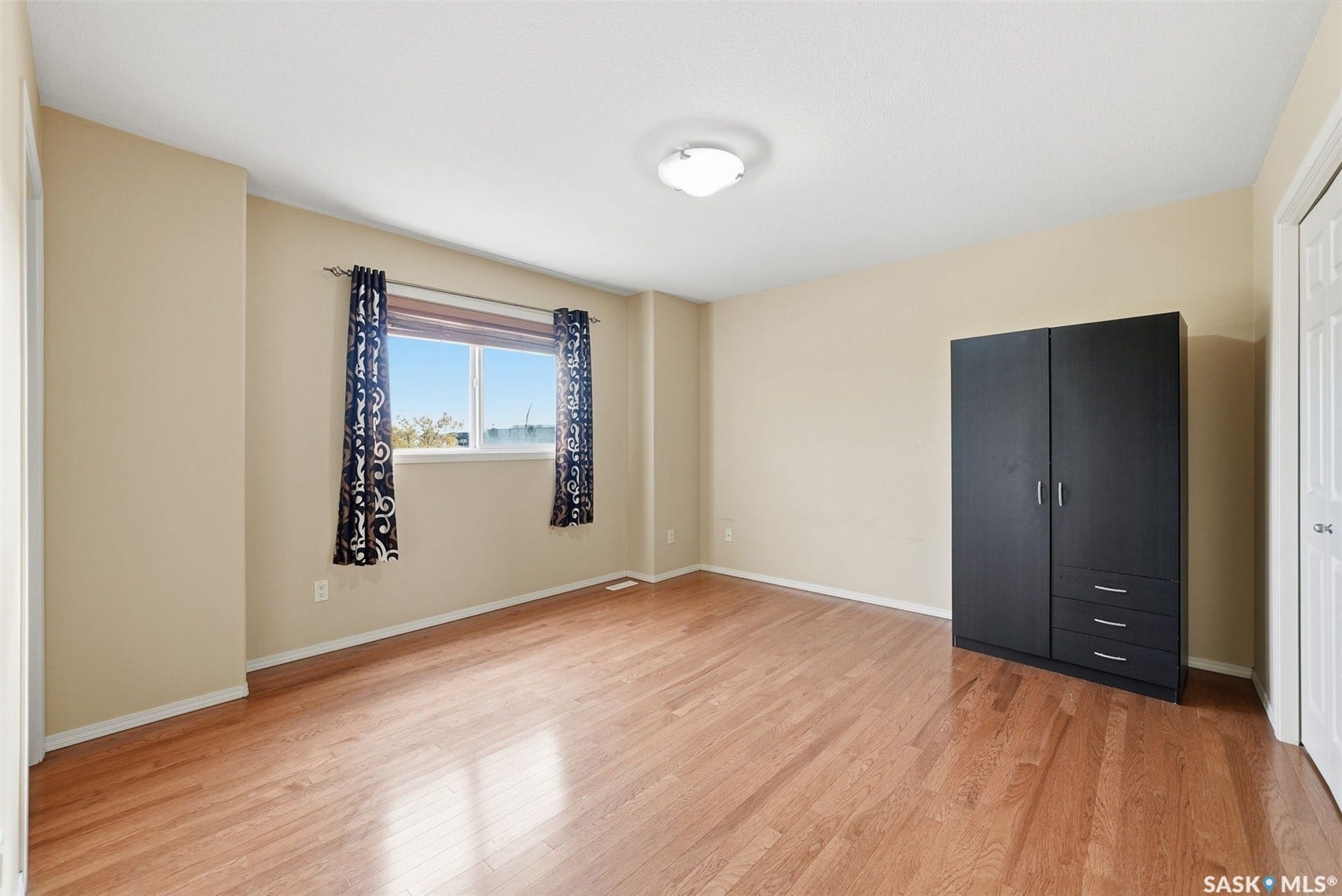 Hardwood-finish flooring, neutral wall tones, and a flush mount ceiling light fixture