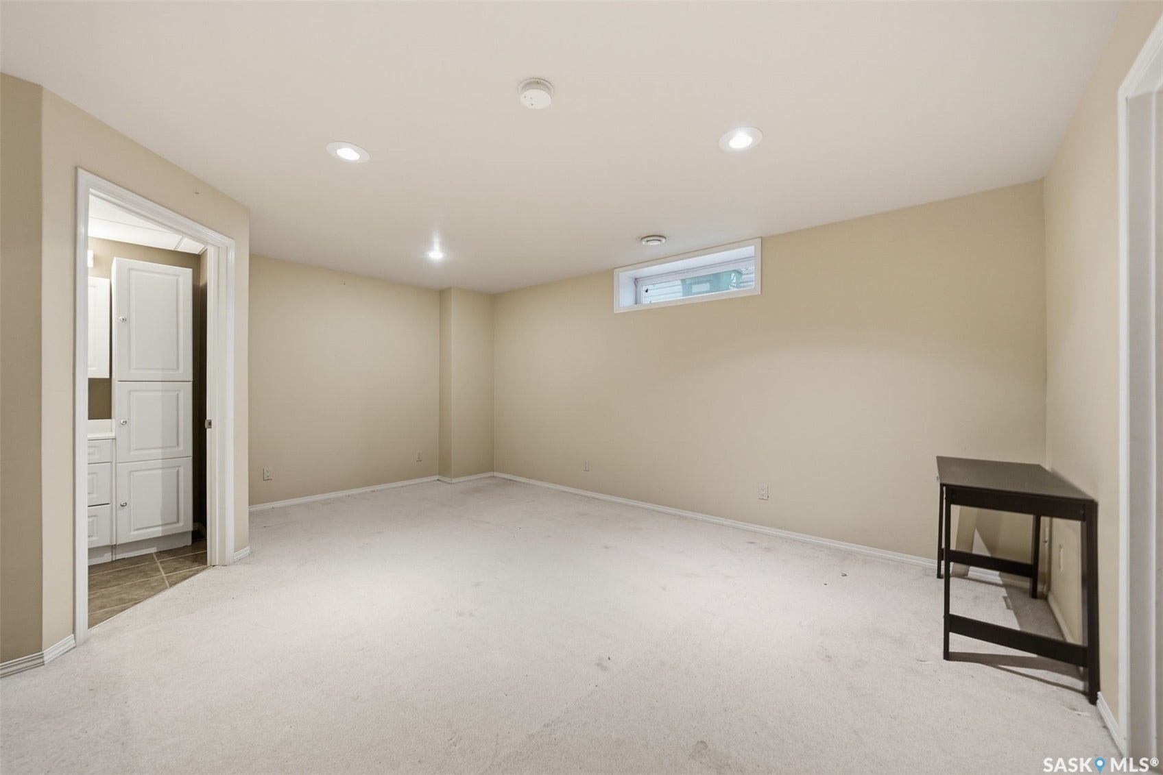 Recessed lighting, wall-to-wall carpeting, and a window provide natural light