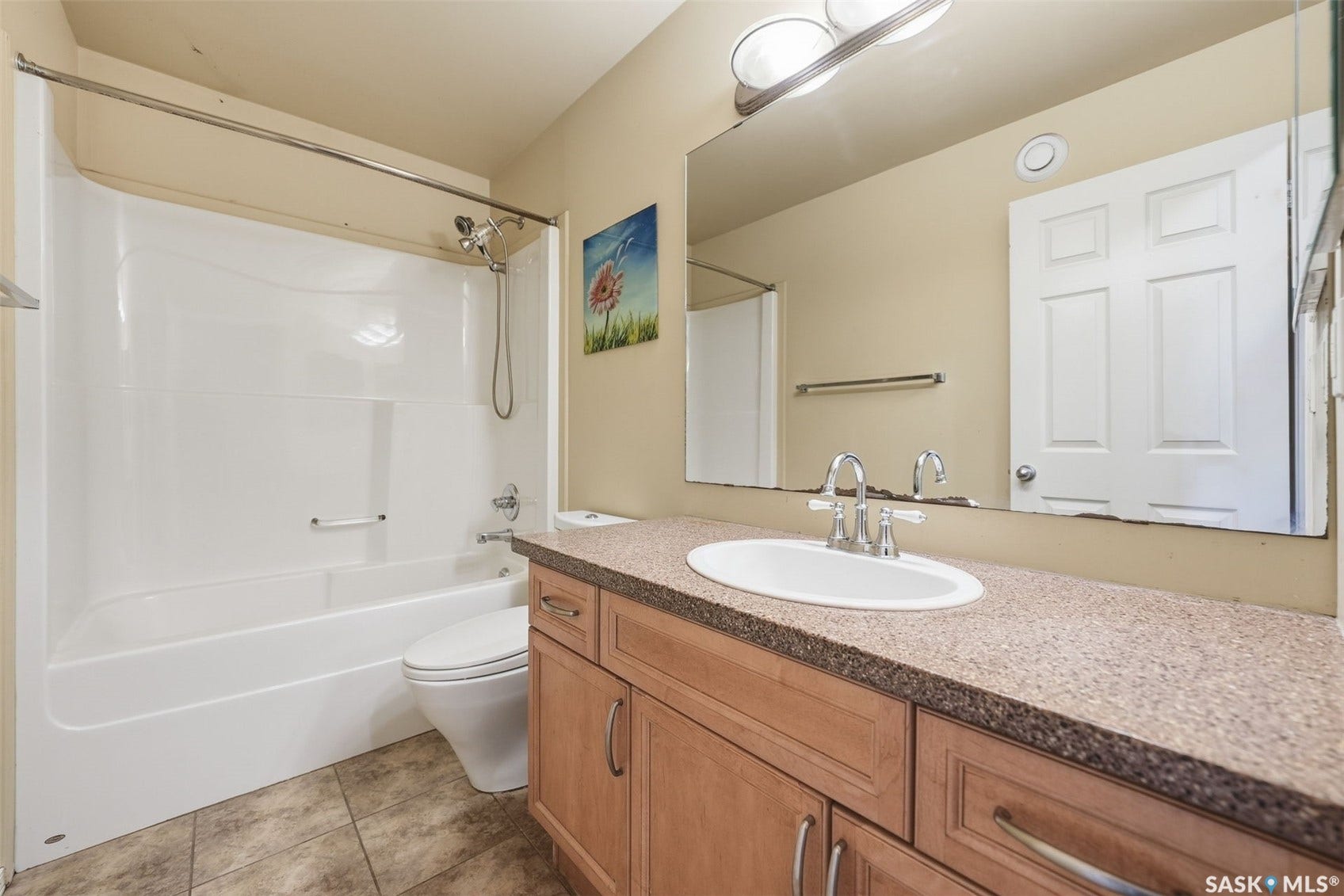 Full bathroom featuring a single vanity with wood-finish cabinetry, a white oval undermount sink, and a speckled countertop