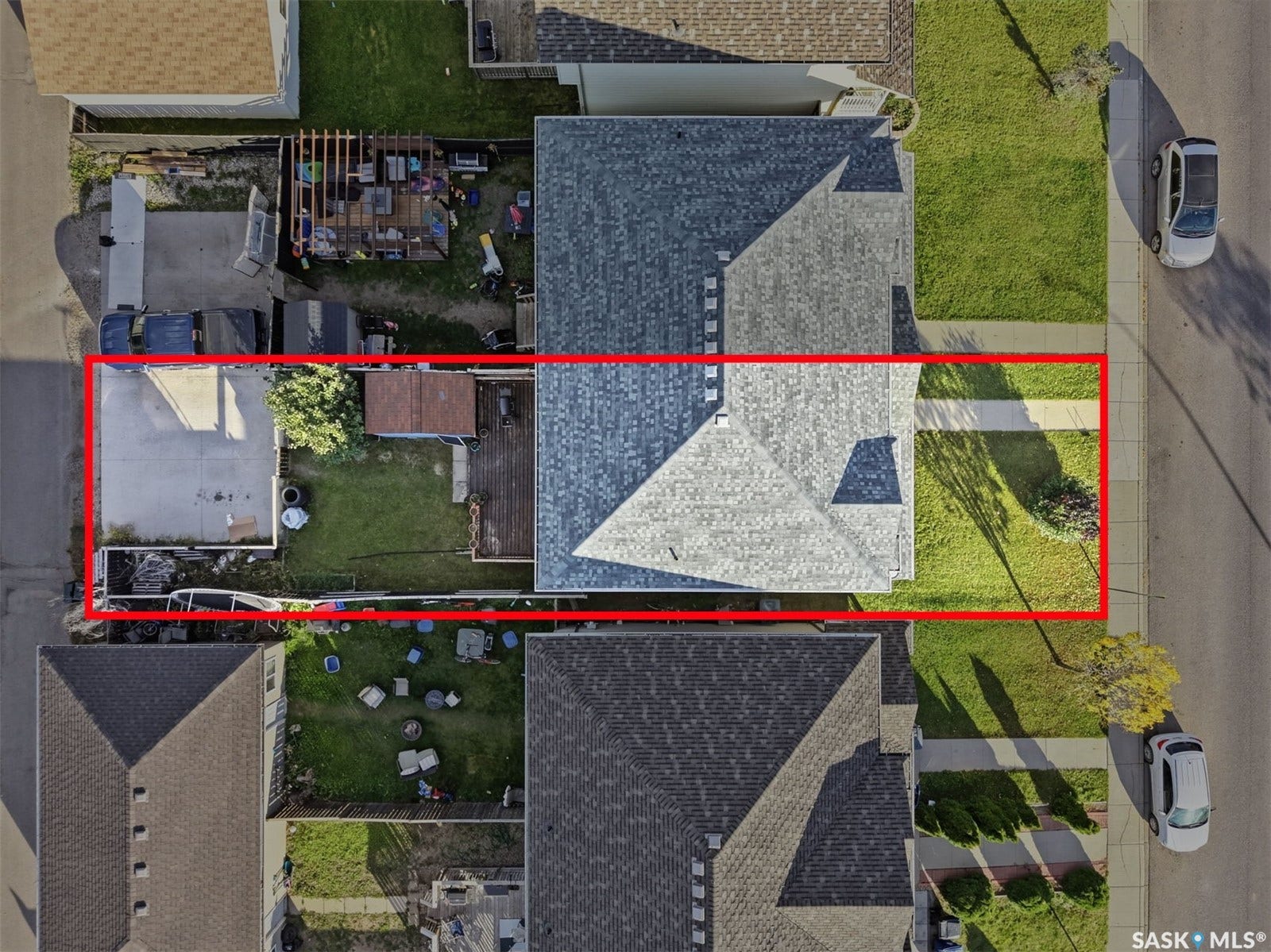 Asphalt shingle roofing, concrete driveway, wood decking, and a grassy lawn area