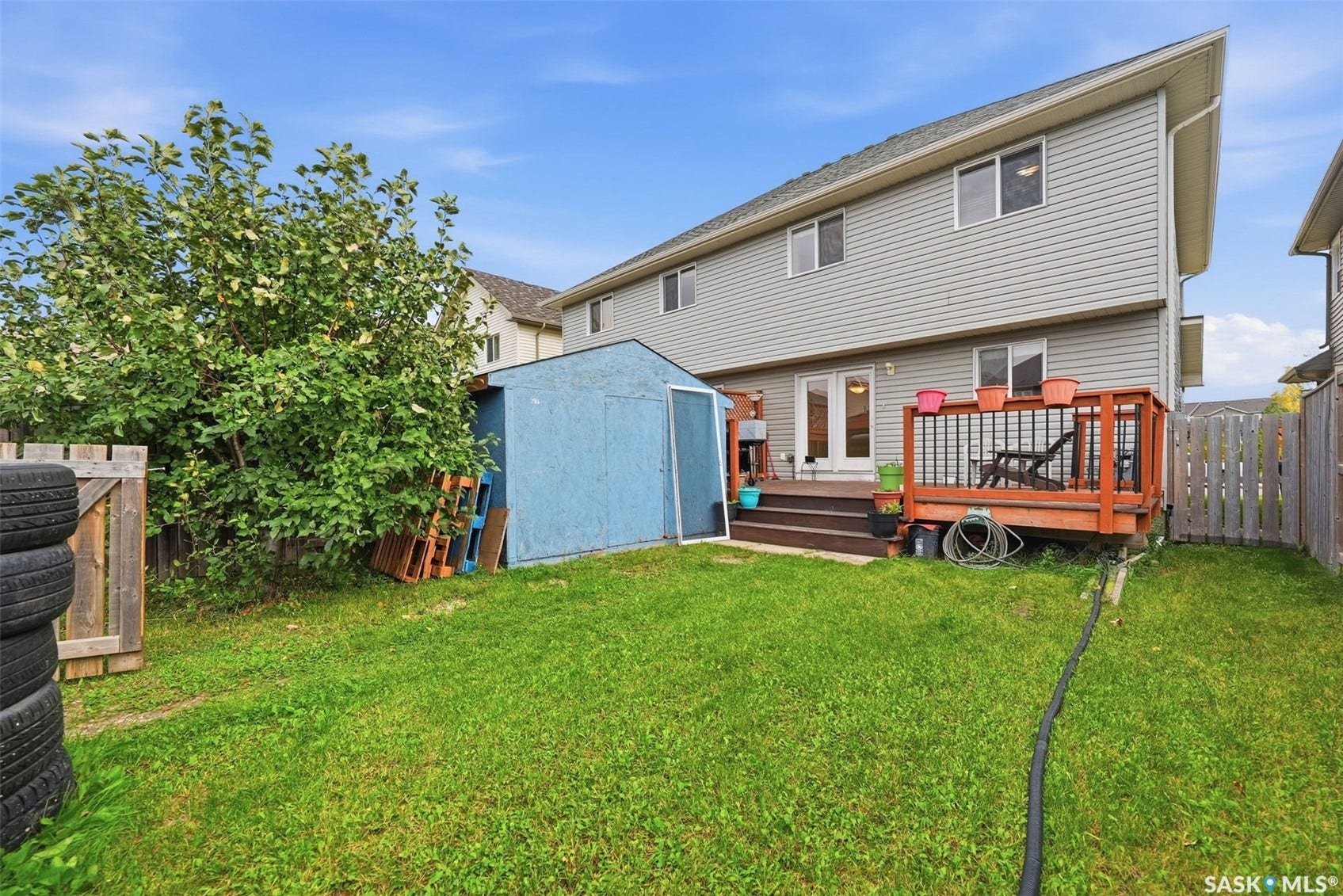 Expansive grassy yard with a wooden deck featuring a railing and steps