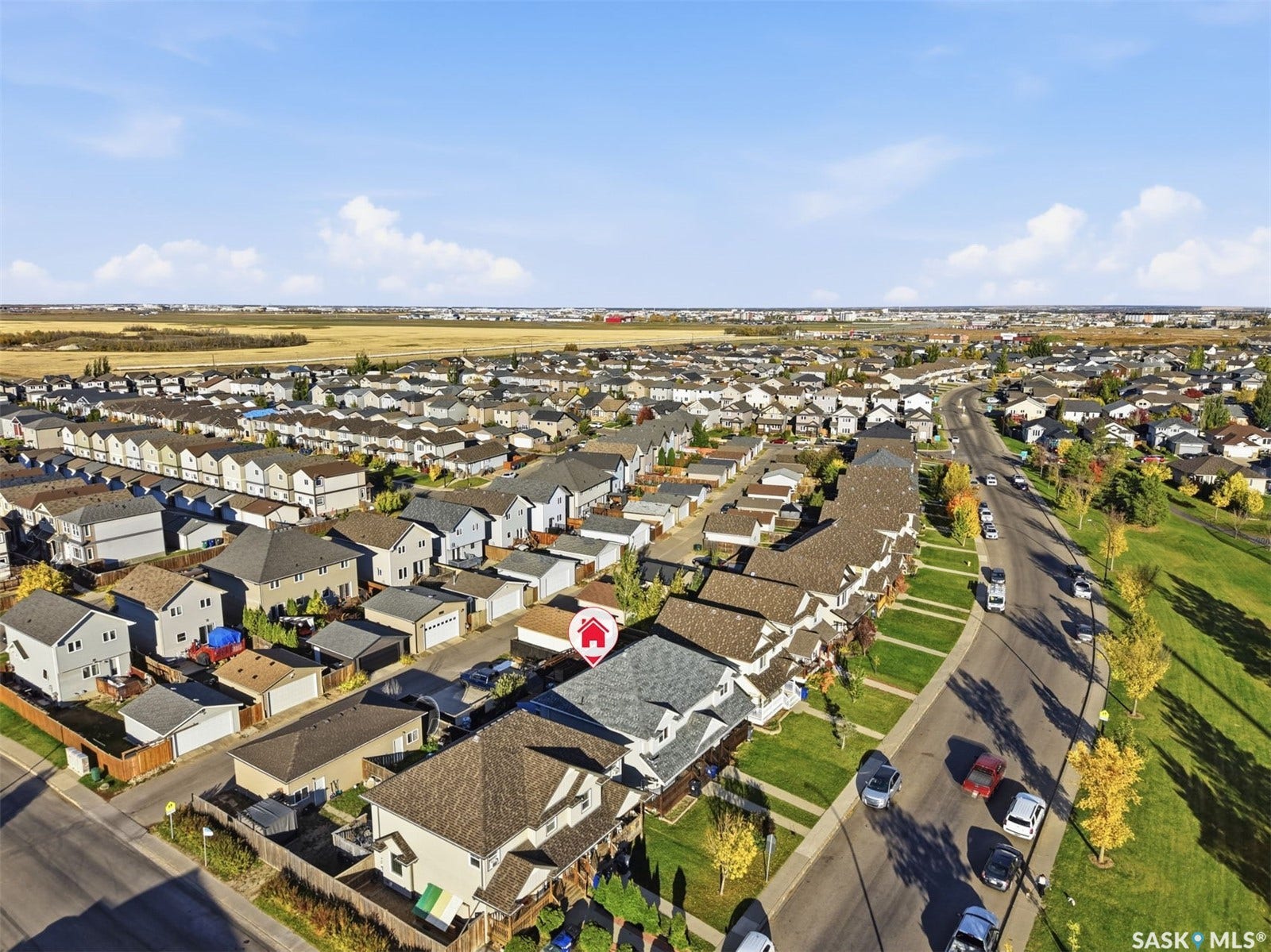 Aerial perspective showcasing a residential area with varied home styles, expansive green spaces, and a clear sky backdrop