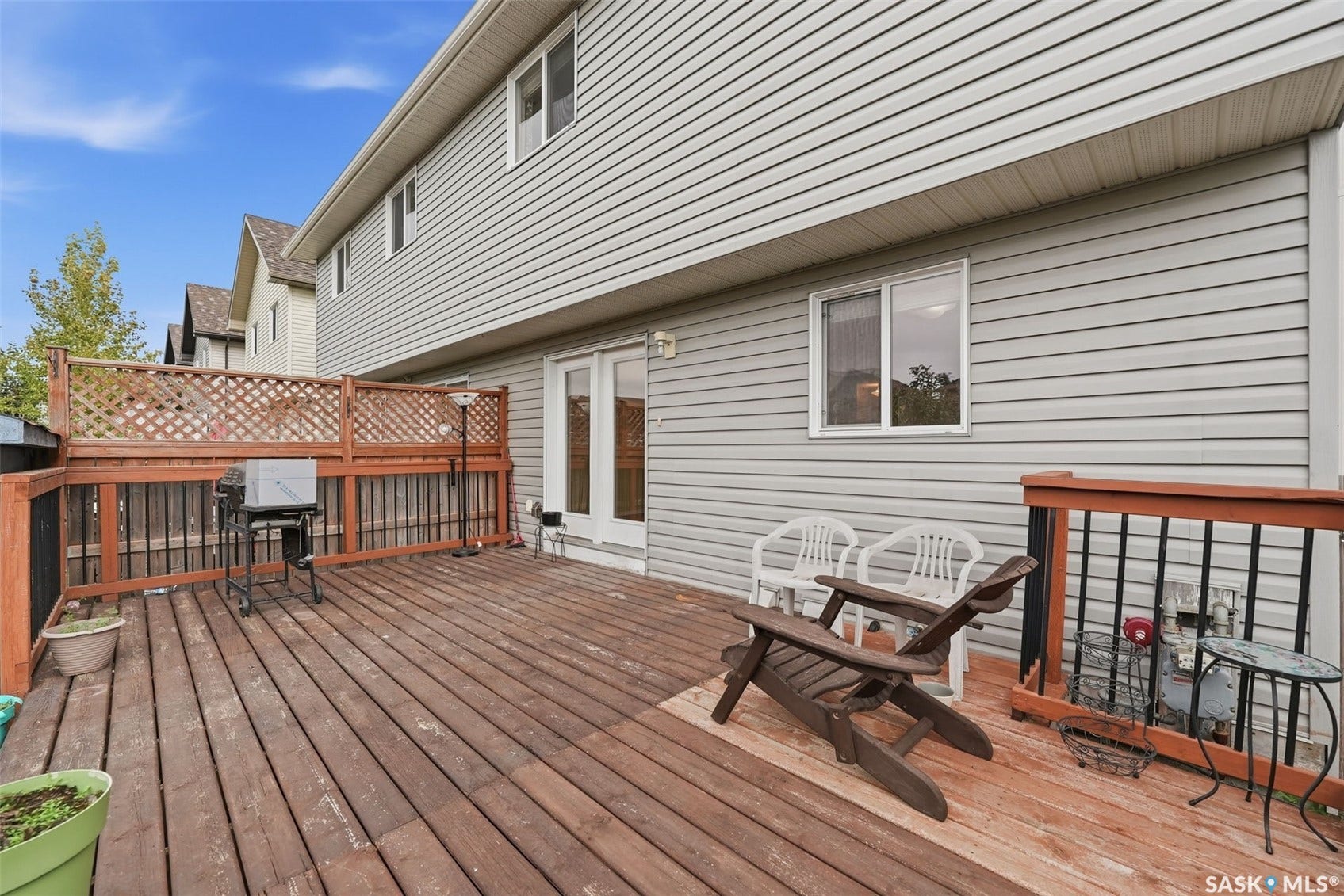 Expansive wood deck with lattice privacy screening, direct access via patio doors, and exterior wall siding