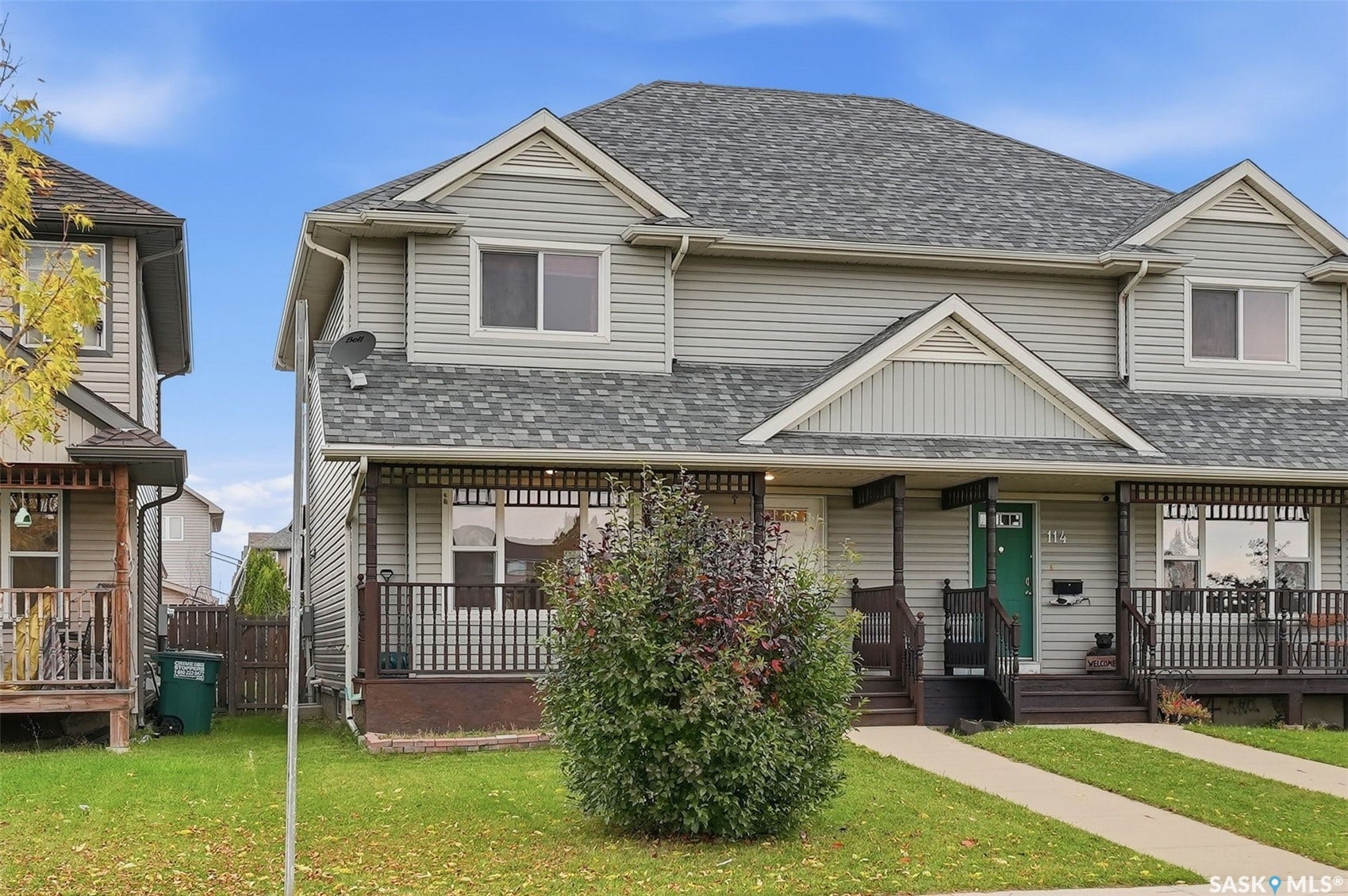 Light grey siding exterior with a dark grey shingle roof, featuring white trim accents and a covered front porch with dark railing
