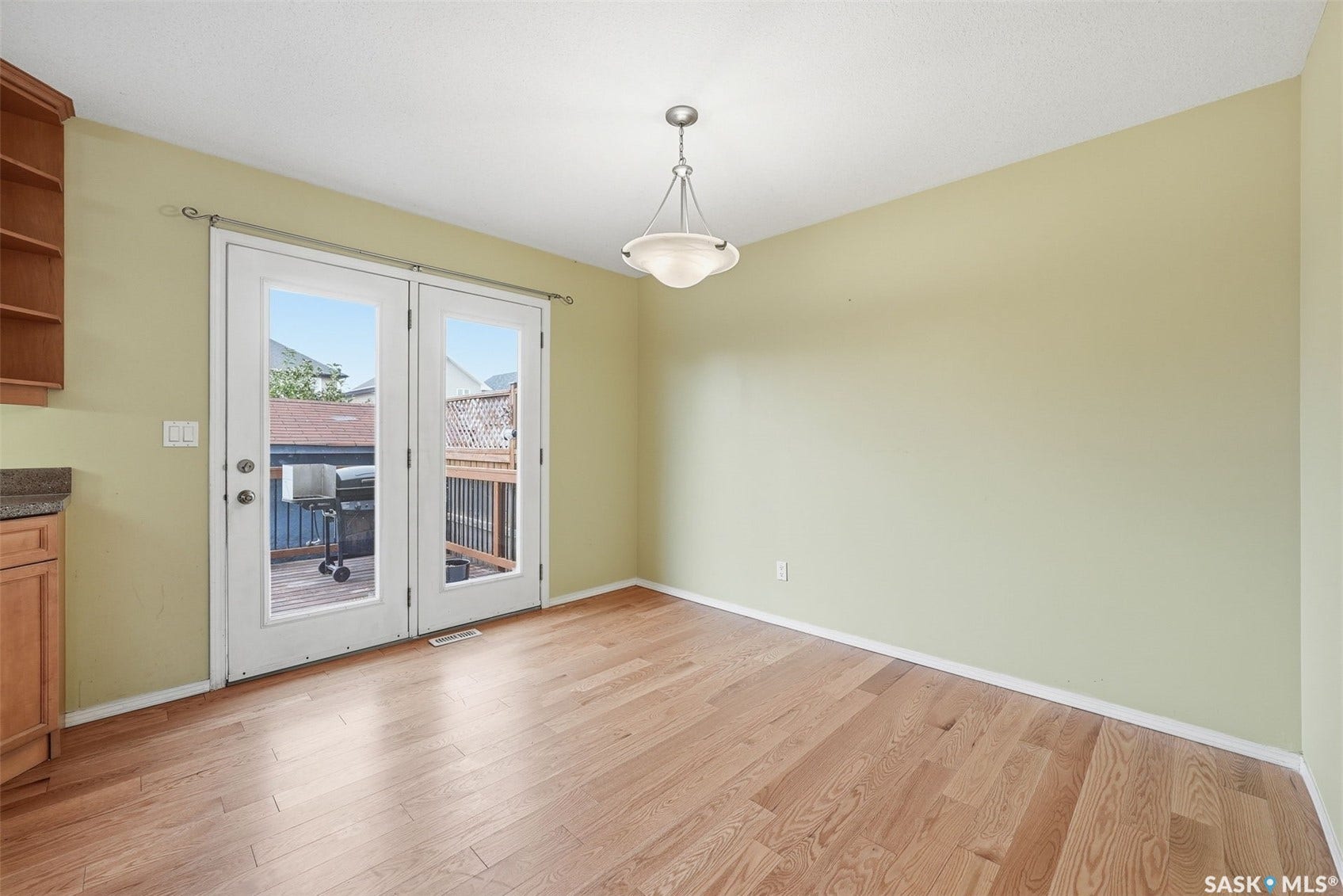 Wood-finish flooring, white French doors, ceiling-mounted light fixture, open shelving, and solid-surface countertop