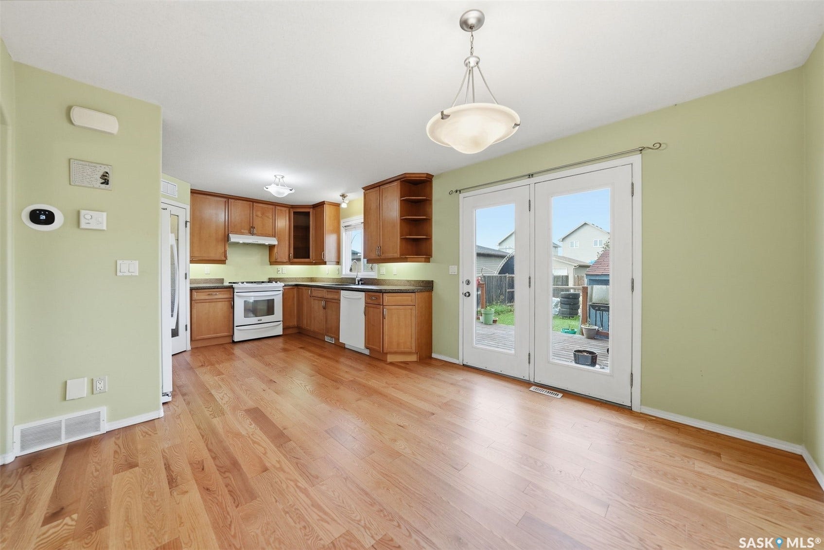 Kitchen and dining area featuring wood-finish flooring, white appliances, and wood cabinetry