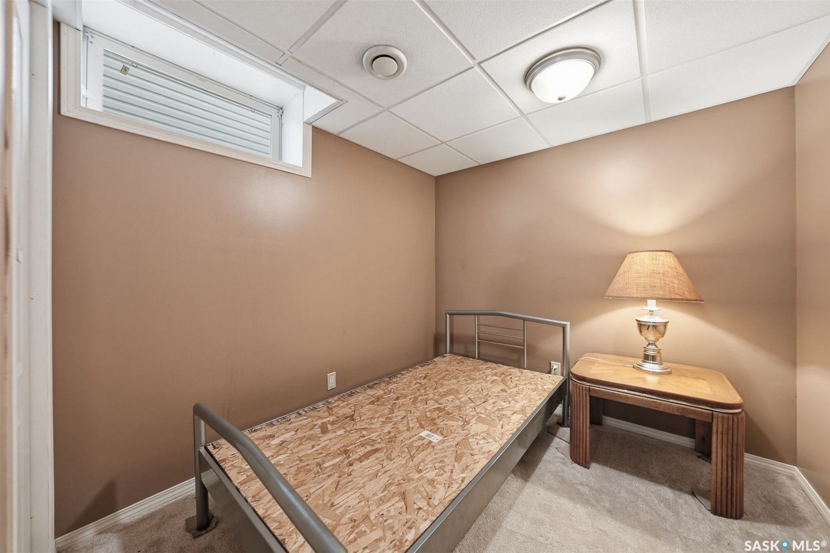 Neutral tone wall paint, carpet flooring, a drop ceiling, and a wall-mounted light fixture