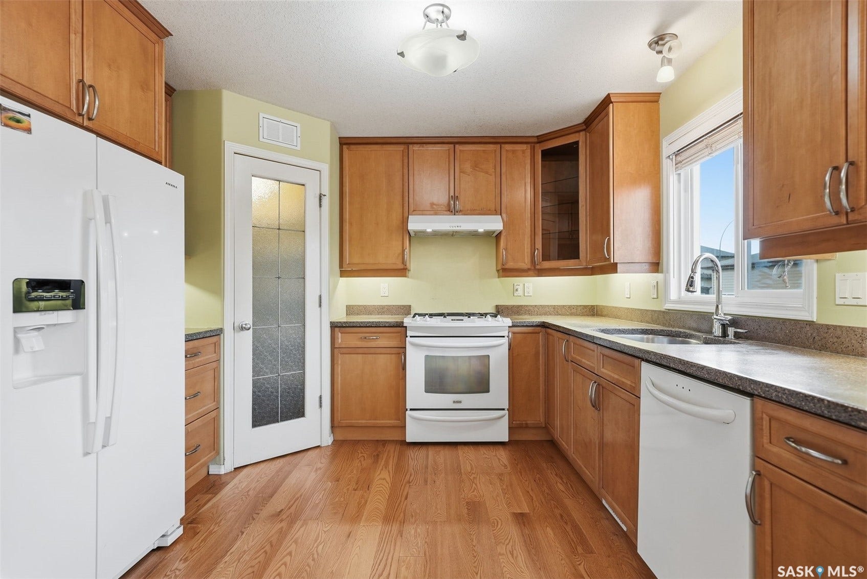 Wood-finish flooring, wood cabinetry with brushed nickel hardware, and stone-look countertops