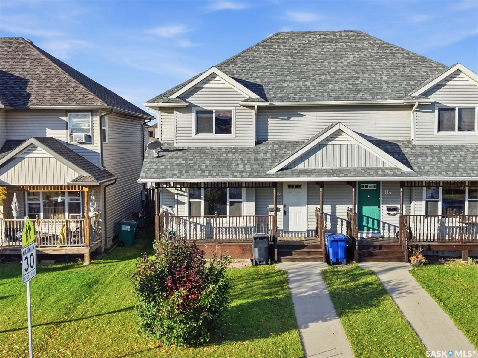 Multi-unit residential property with grey siding, a front porch, and a pitched shingle roof