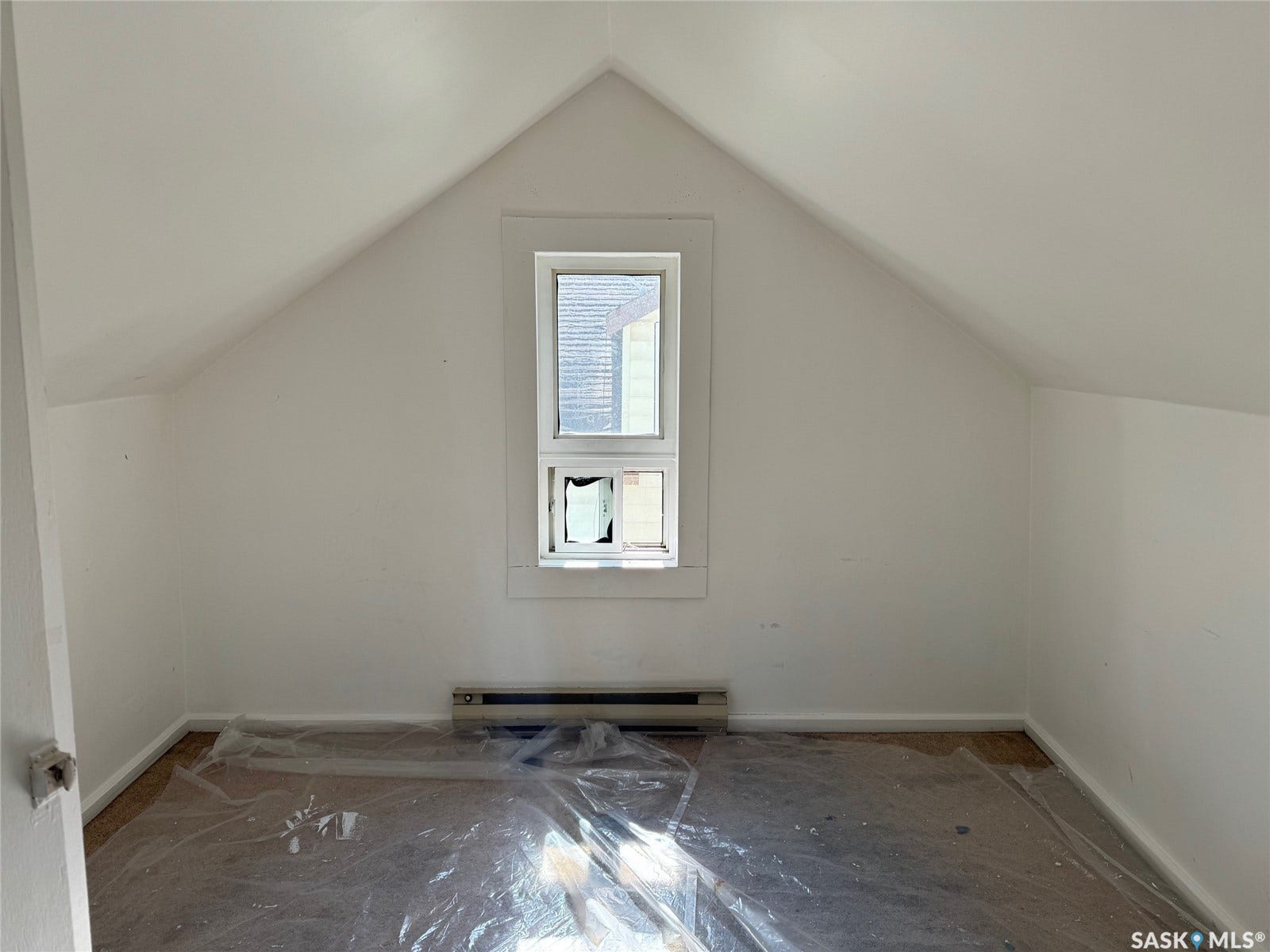 White painted walls with sloped ceilings and a single window