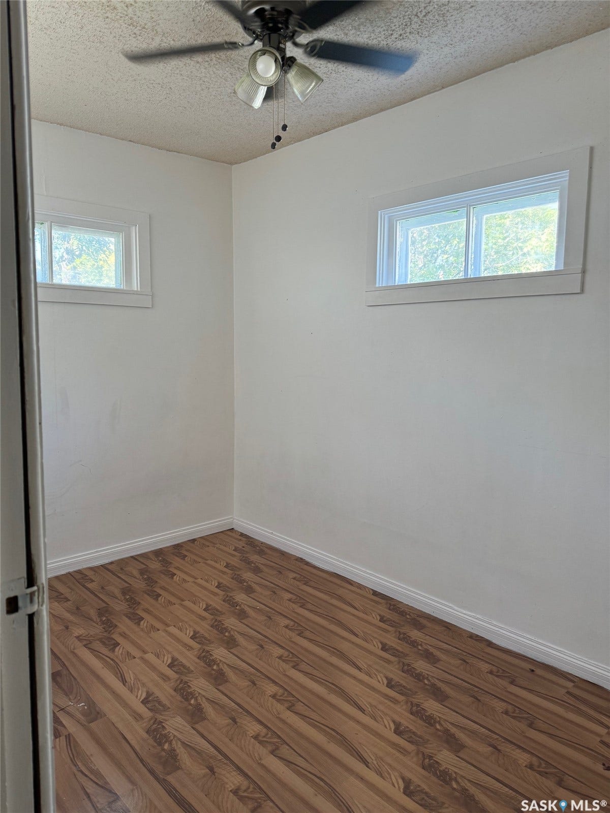 Wood-finish flooring with white baseboards and painted walls