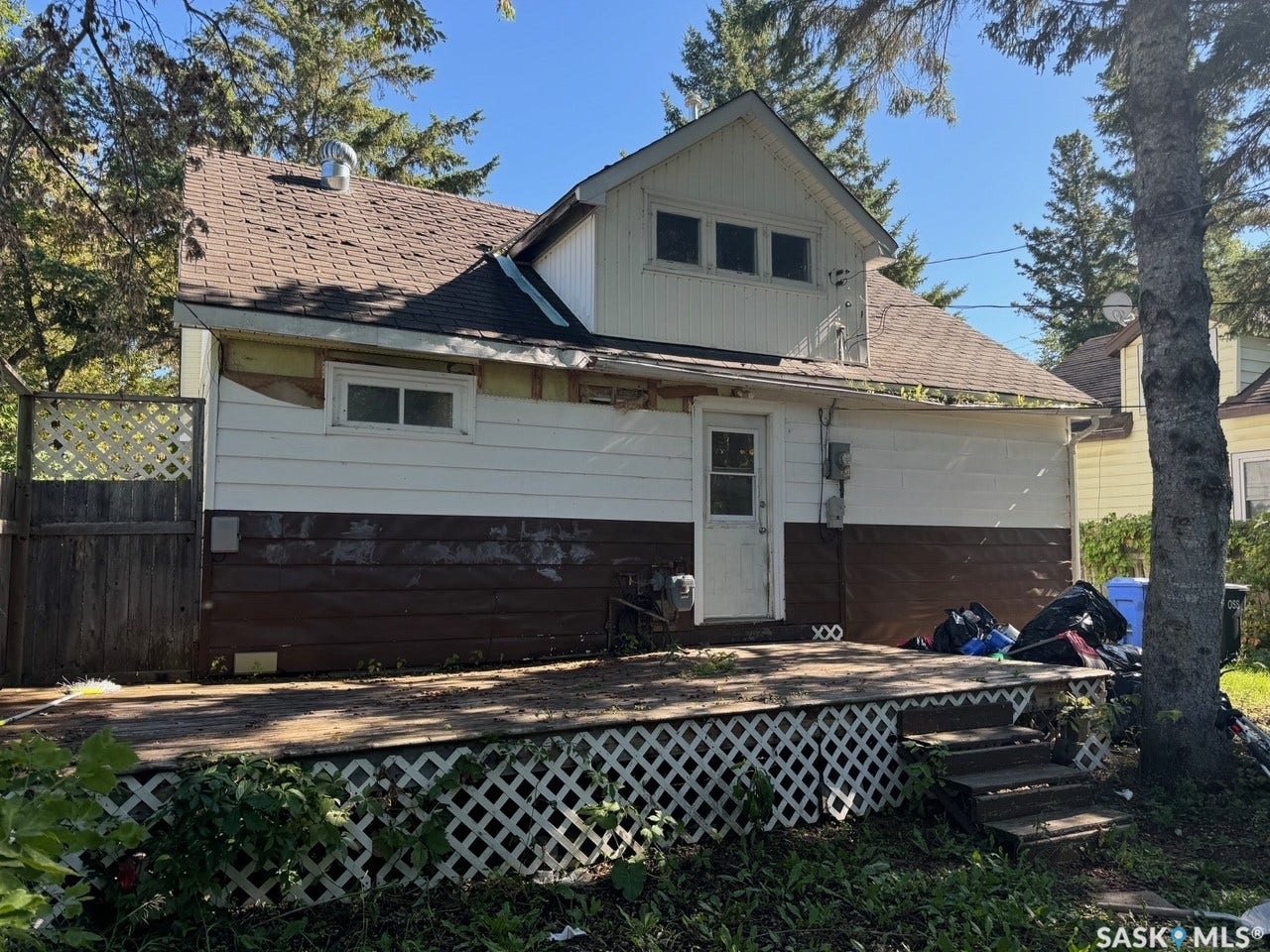 Charming mid-century home featuring a gabled roofline with brick chimney, horizontal siding exterior, and multi-pane windows