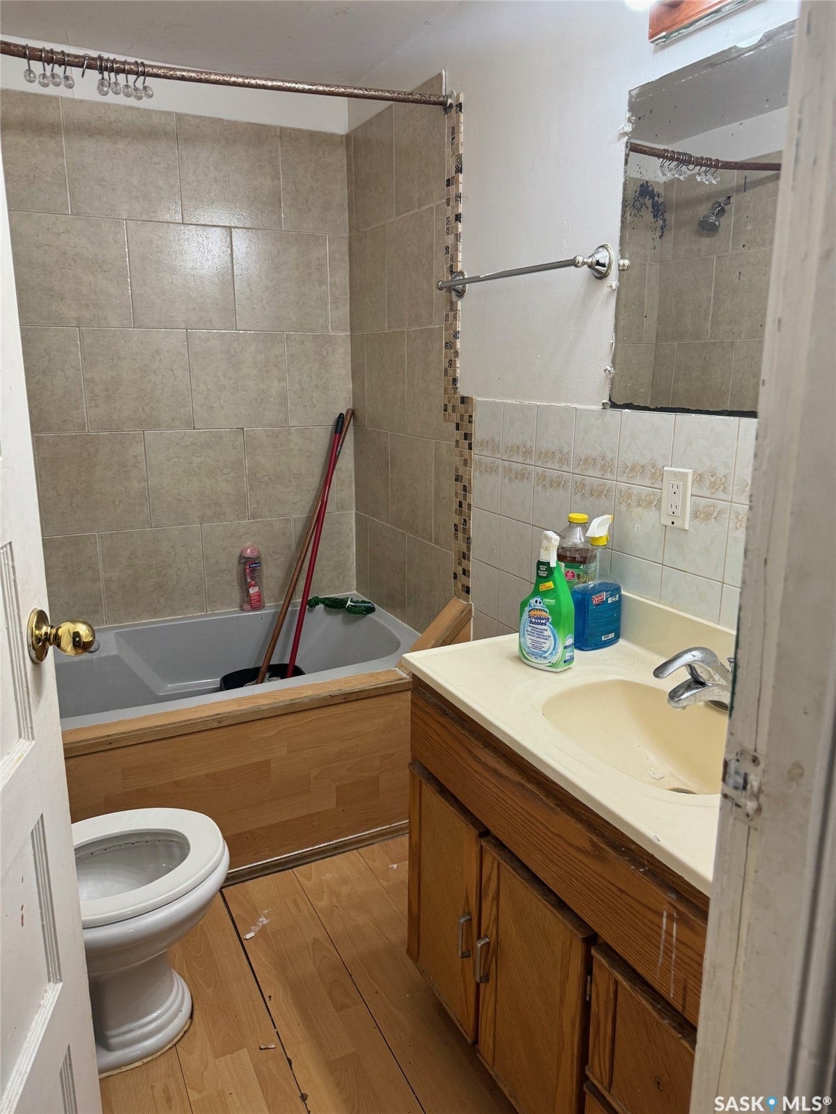Full bathroom featuring a wood-finish vanity with dual-sink configuration, ceramic tile surround in the tub/shower area, and ceramic tile flooring throughout