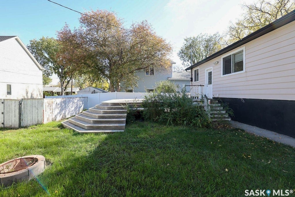 Rear exterior featuring light-colored siding, a white door, and a white-railed deck with stairs to grade