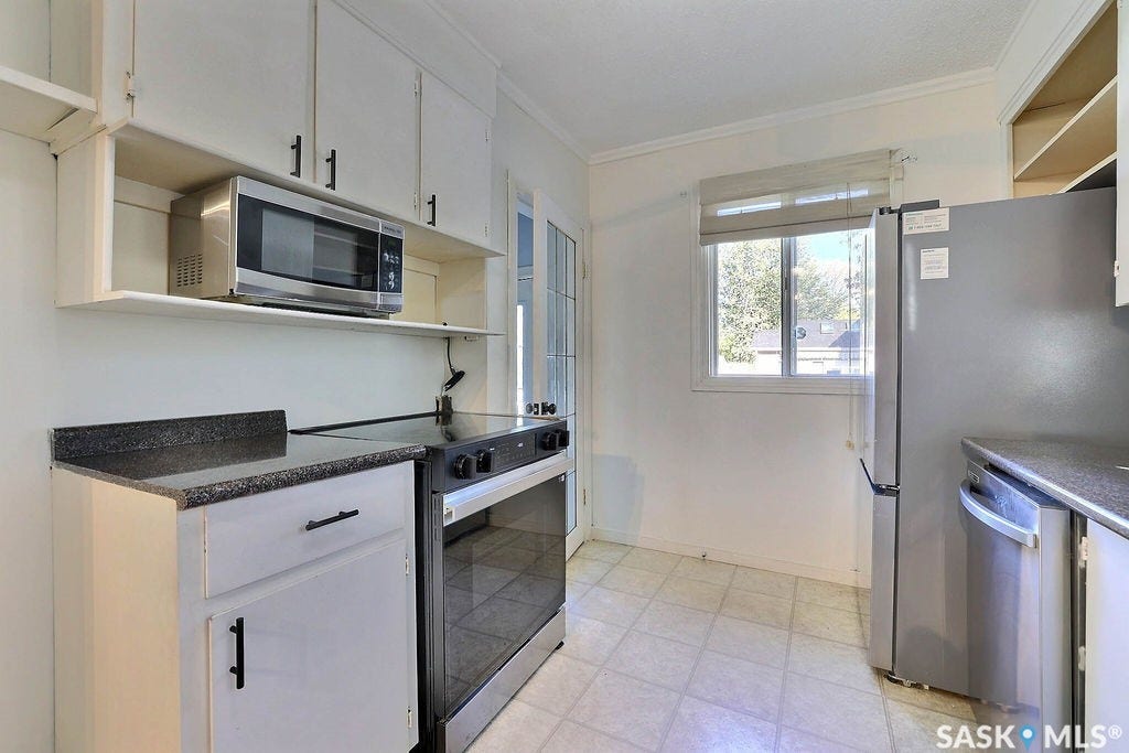 Kitchen featuring white cabinetry, dark countertops, a stainless steel microwave, and a stainless steel range